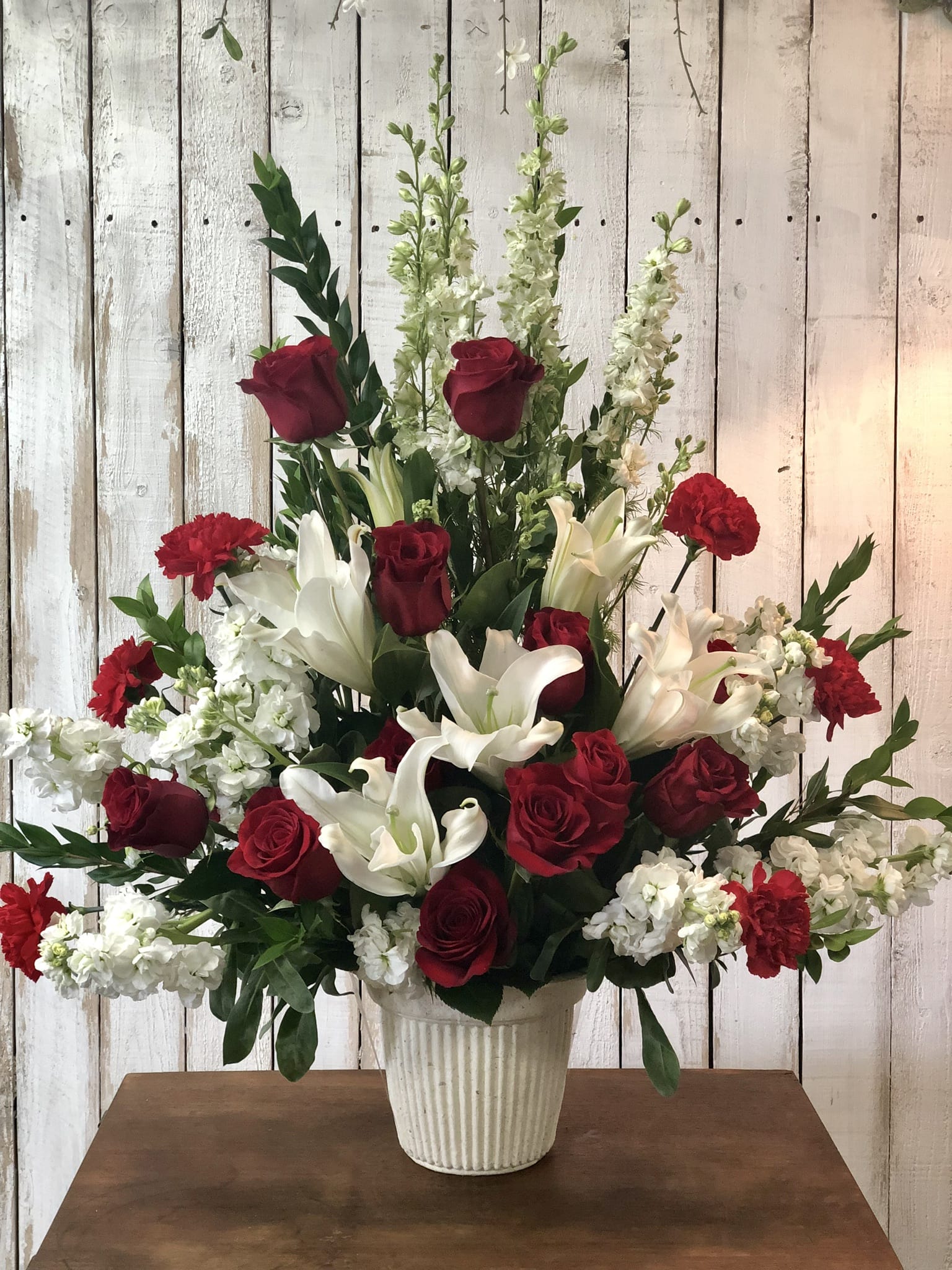  Memories  - Memories is a fan shaped one sided arrangement of white stargazers, Larkspur stock cushion Poms and red roses this arrangement can be made in any color 