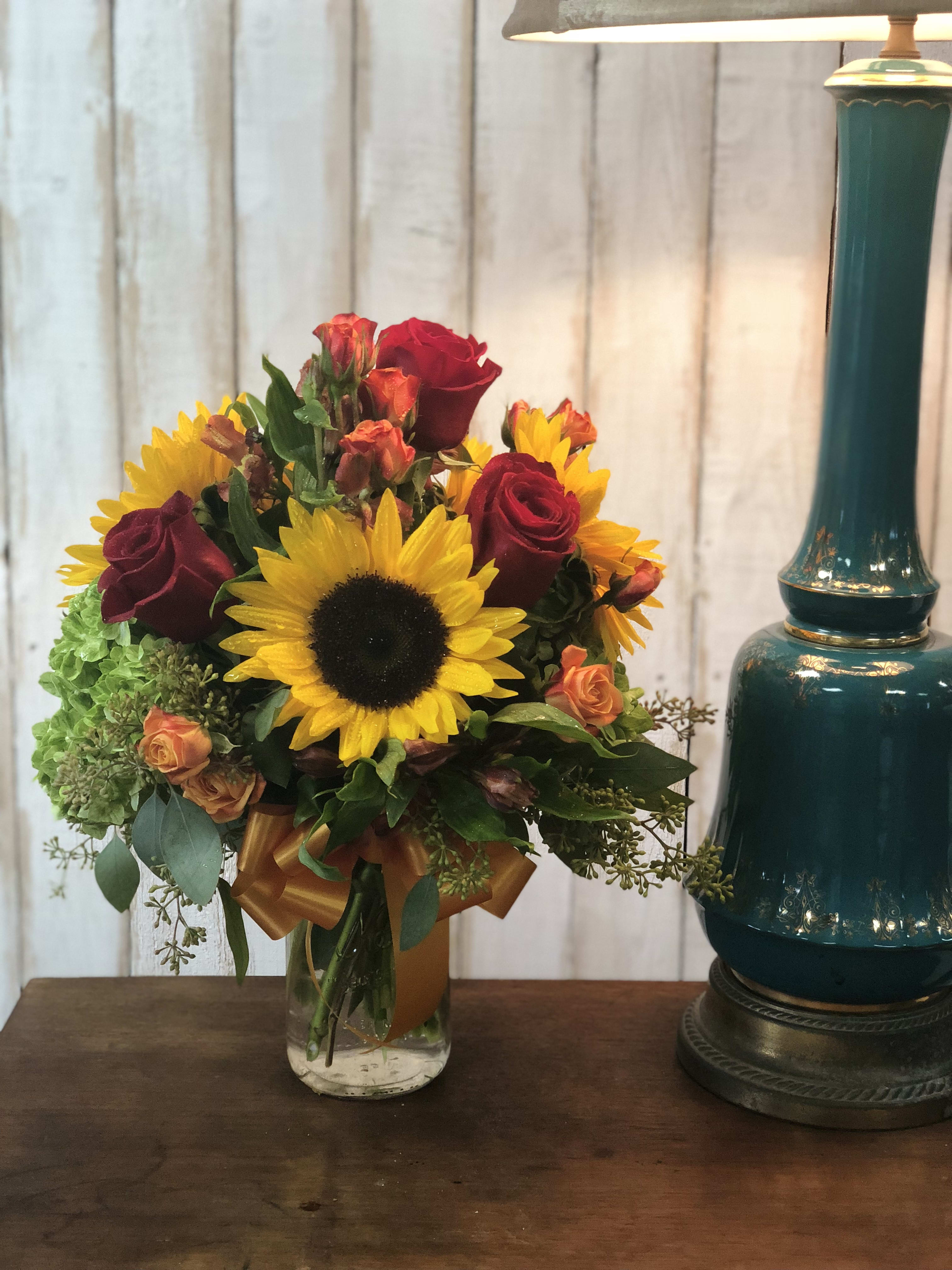 Bouquet of sunflowers and red roses in a glass vase