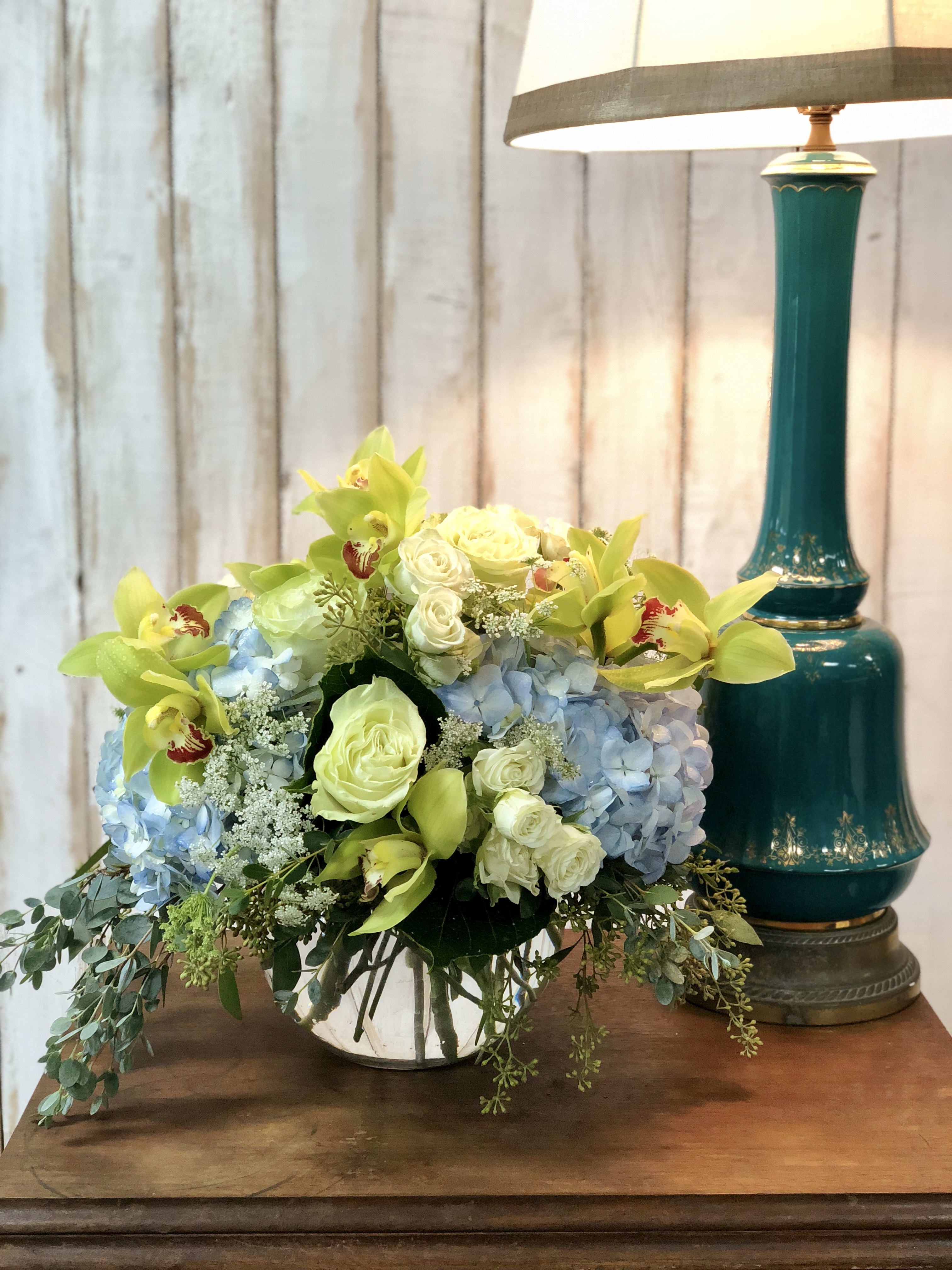 Bountiful Orchids - Bountiful Orchids includes a lovely mix of blue hydrangea, green cymbidium orchids, white roses, and spray roses. 