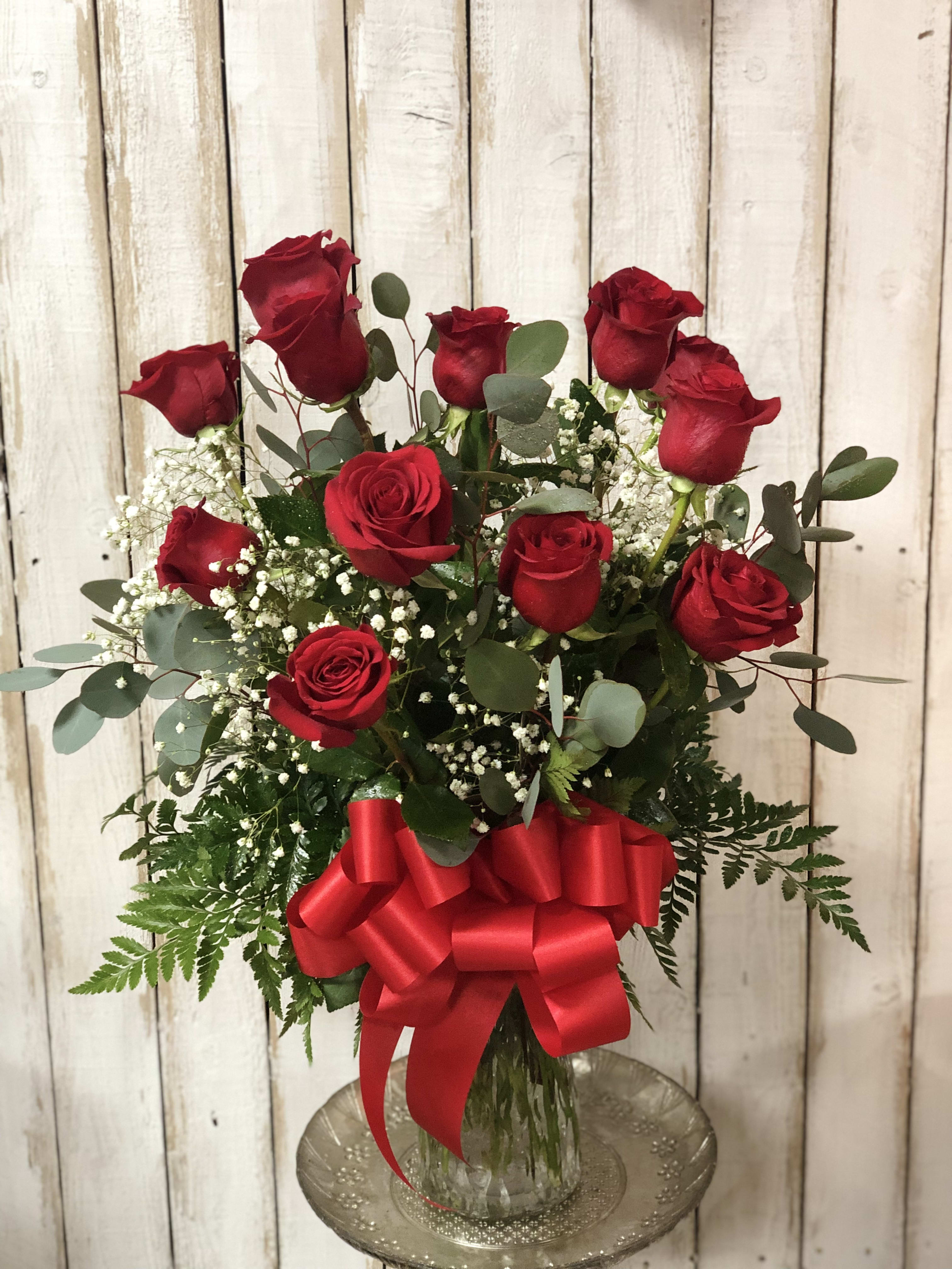 Red roses in a glass vase with a large red bow