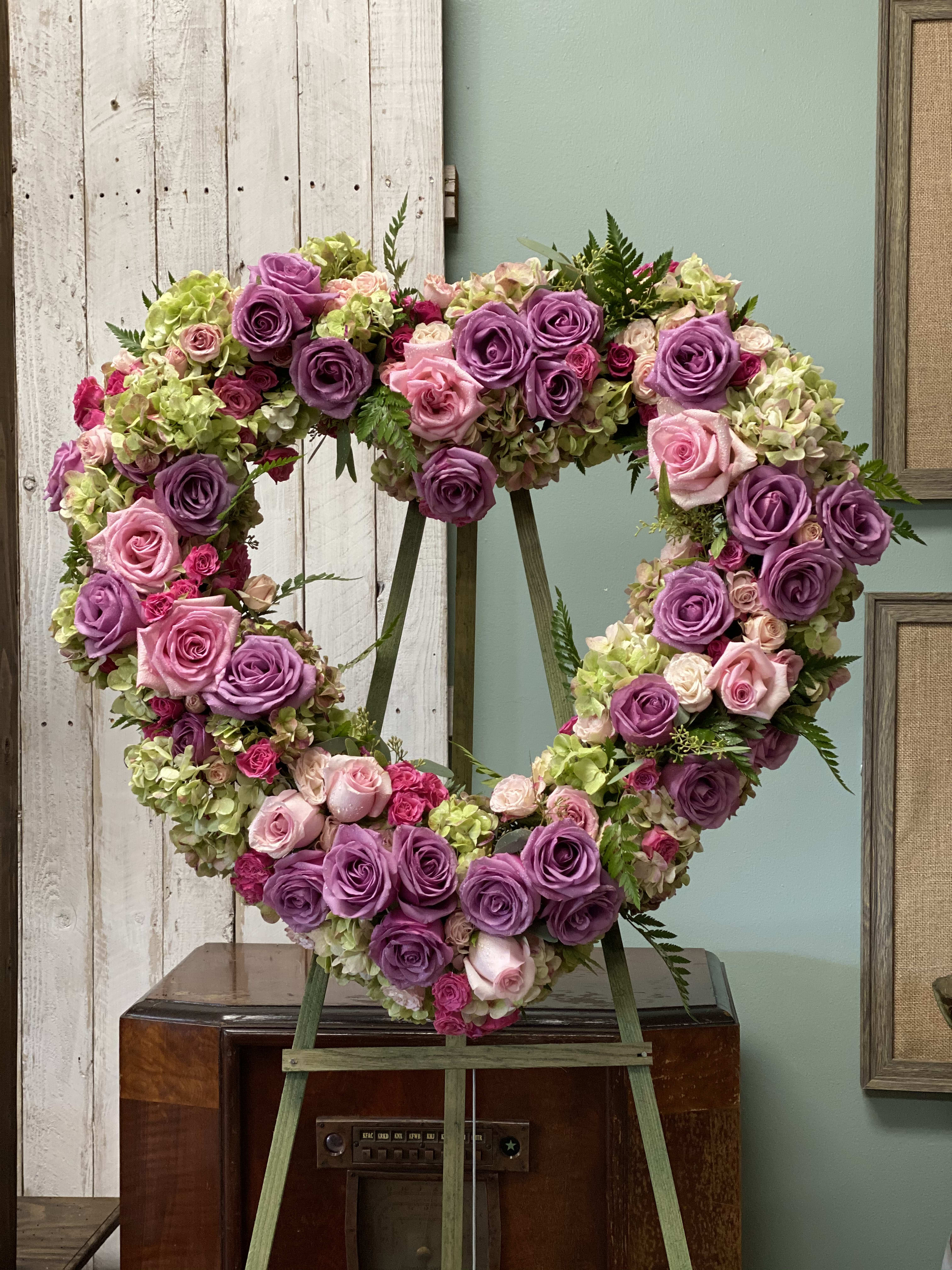 Lavender Heart - This open heart is designed with lavender and pink roses, cushion poms, carnations, spray roses and hydrangeas.