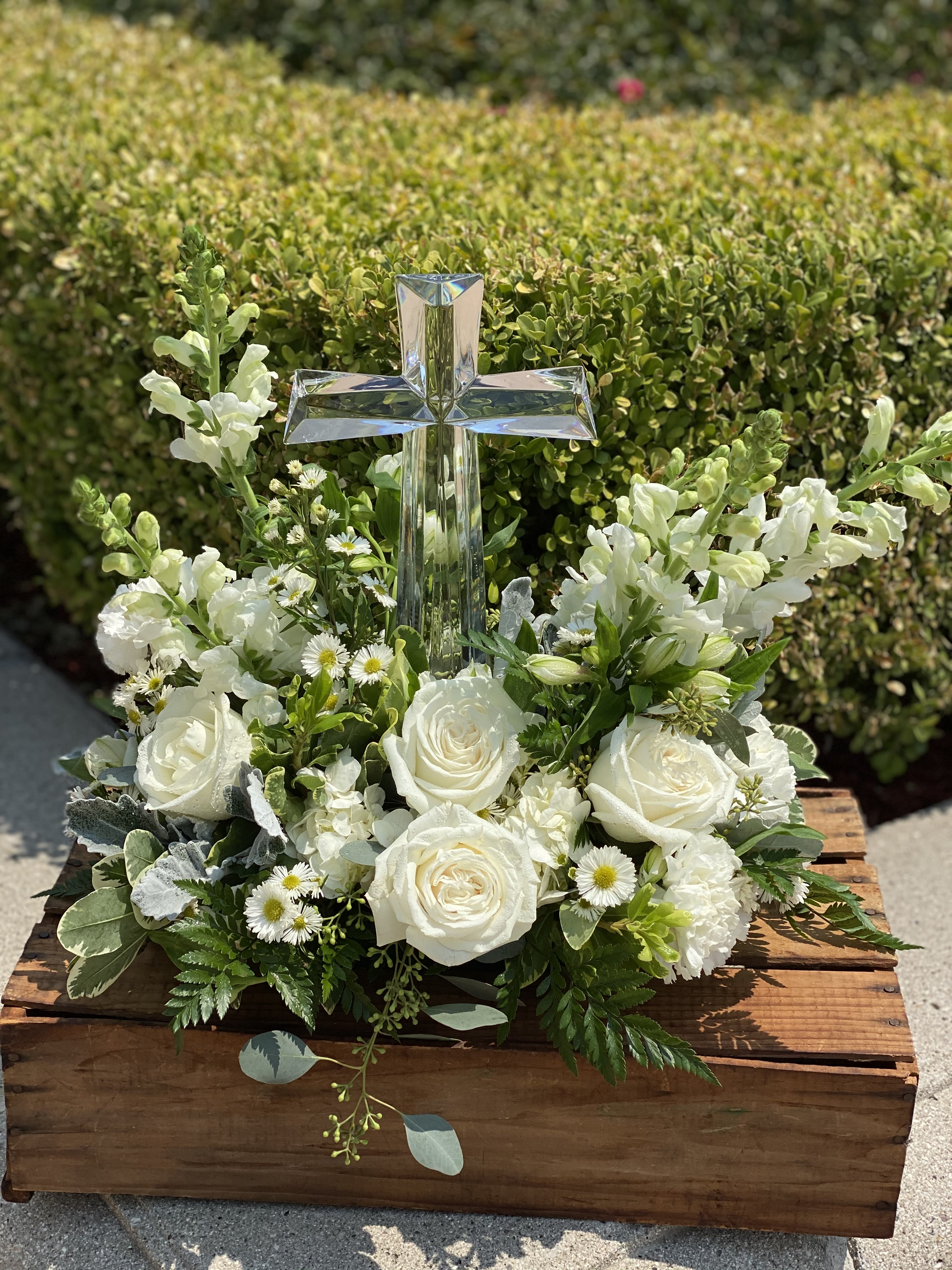 White floral arrangement with a clear cross centerpiece in a wooden box