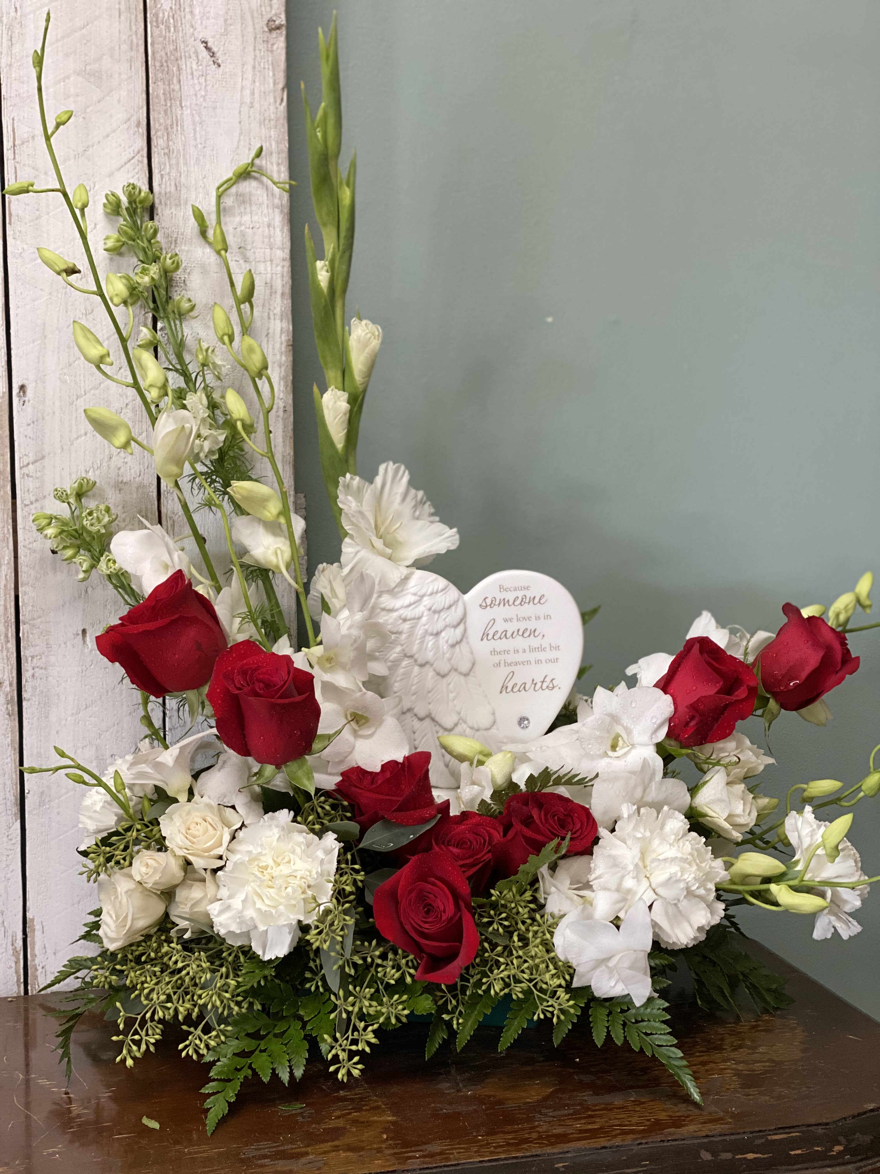 Haven's Heart  - This stunning arrangement is elegantly designed with red roses, gladiolas, orchids, lilies and a keepsake heart.  Message on sculpt reads: "Because someone we love is in heaven, there is a little bit of heaven in our hearts."