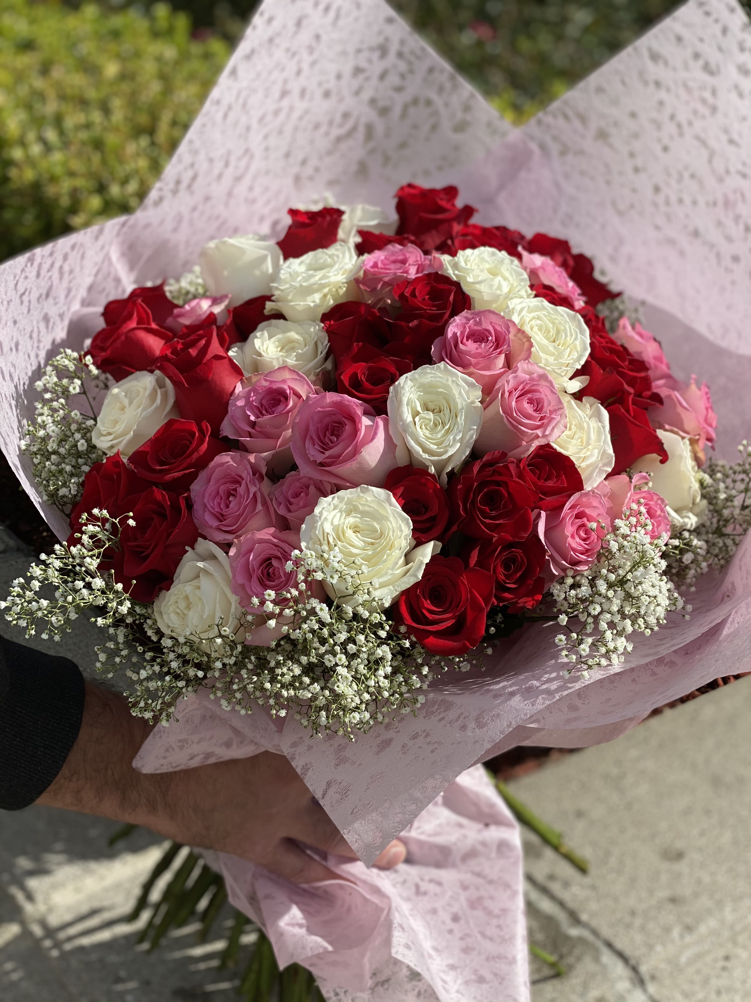 Bouquet of red, pink, and white roses wrapped in pink paper
