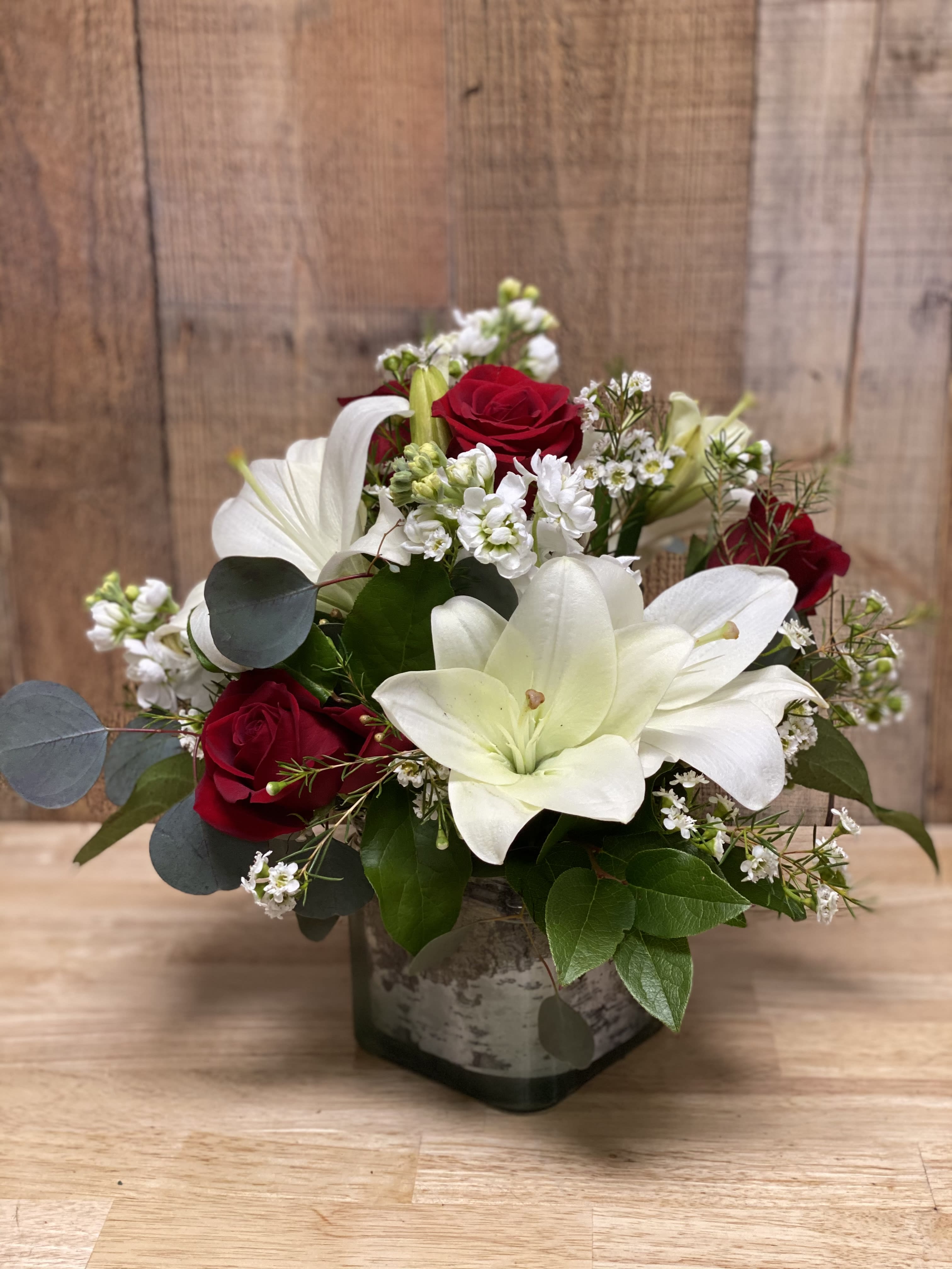 Red roses and white lilies arranged in a square vase