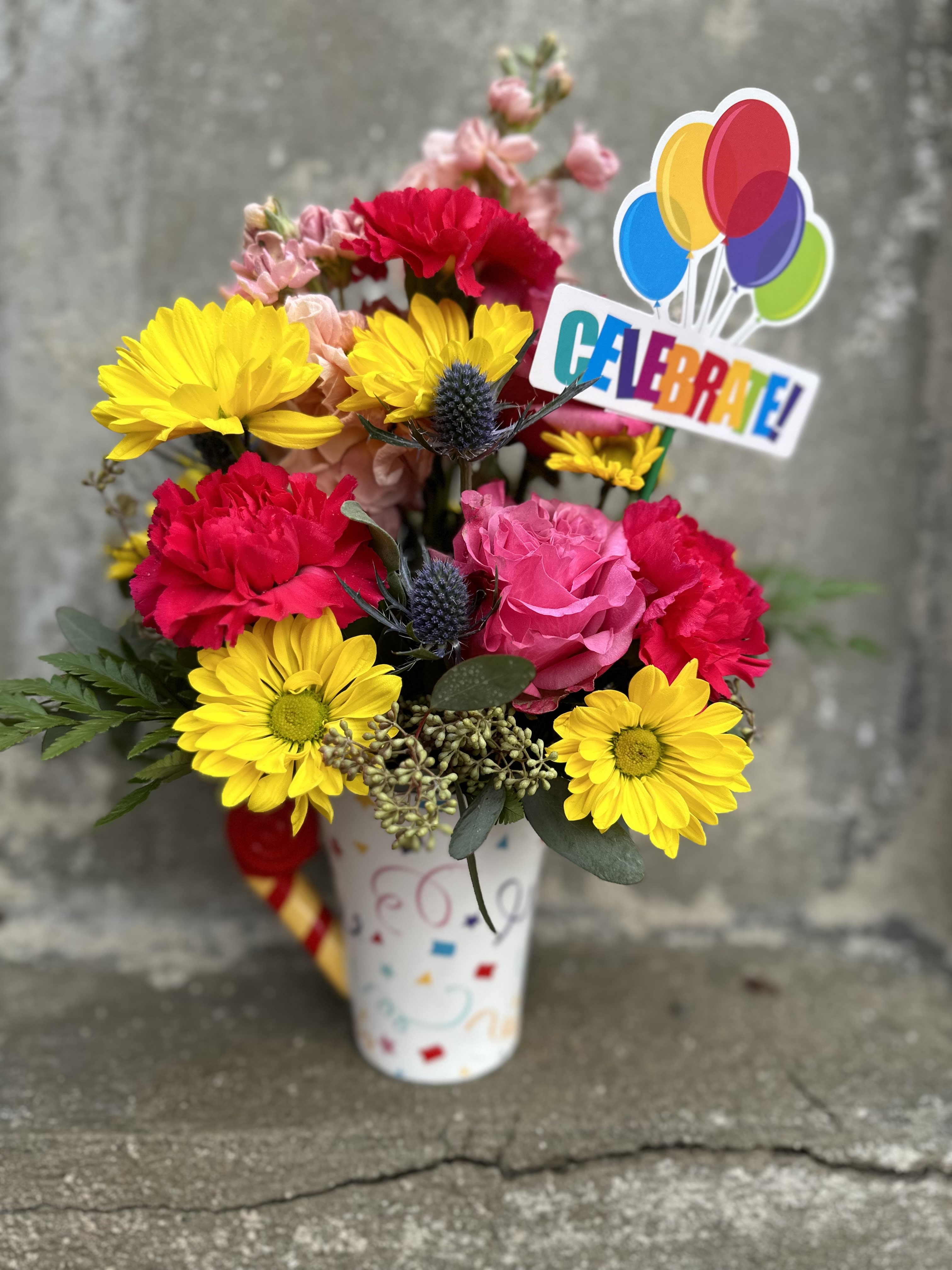 Bright mixed bouquet in a decorated vase with a colorful "Celebrate!" topper