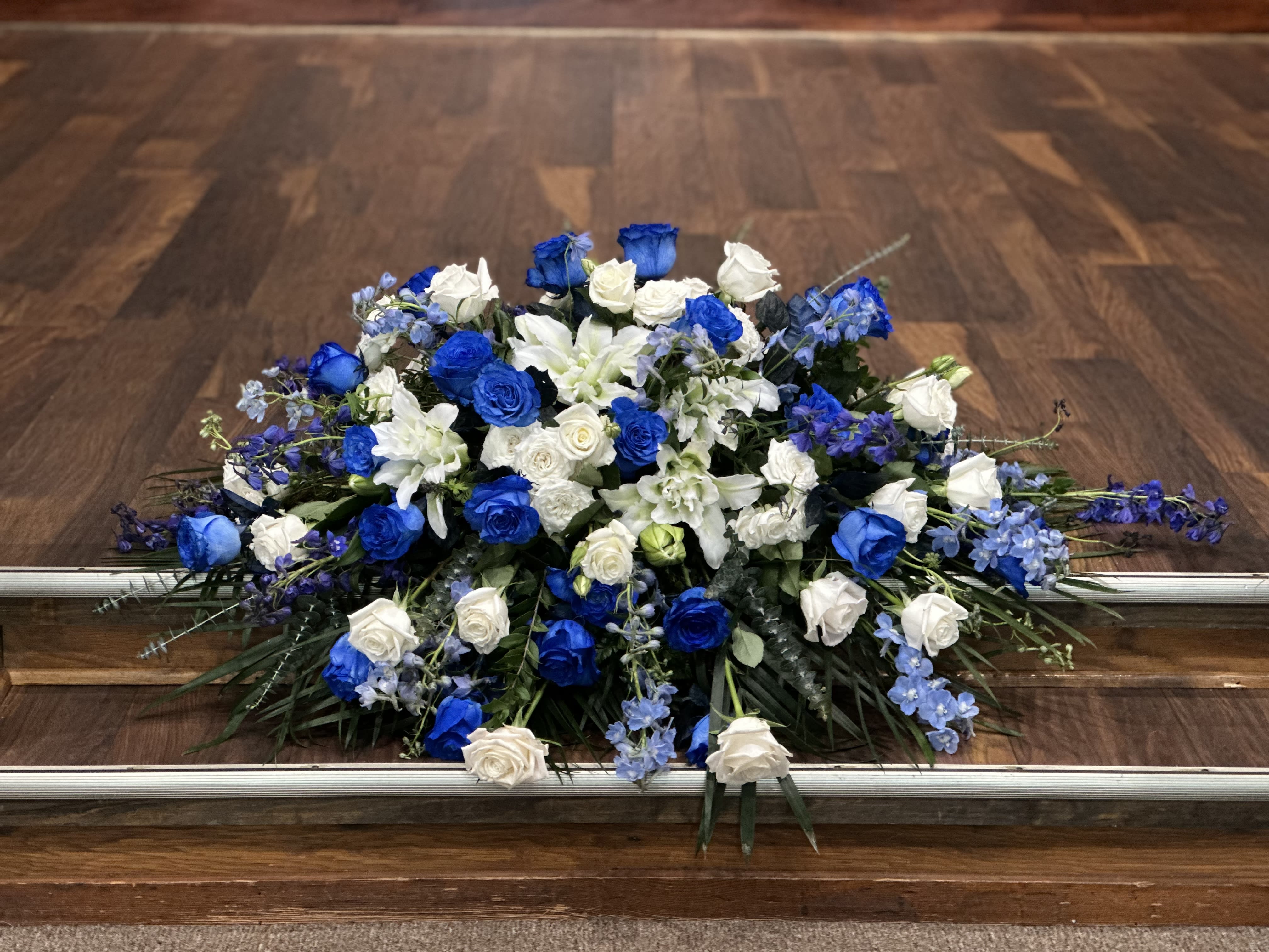 Blue roses - Casket spray flower arrangement with blue Delphinium blue roses, white roses lilies mums and carnations 