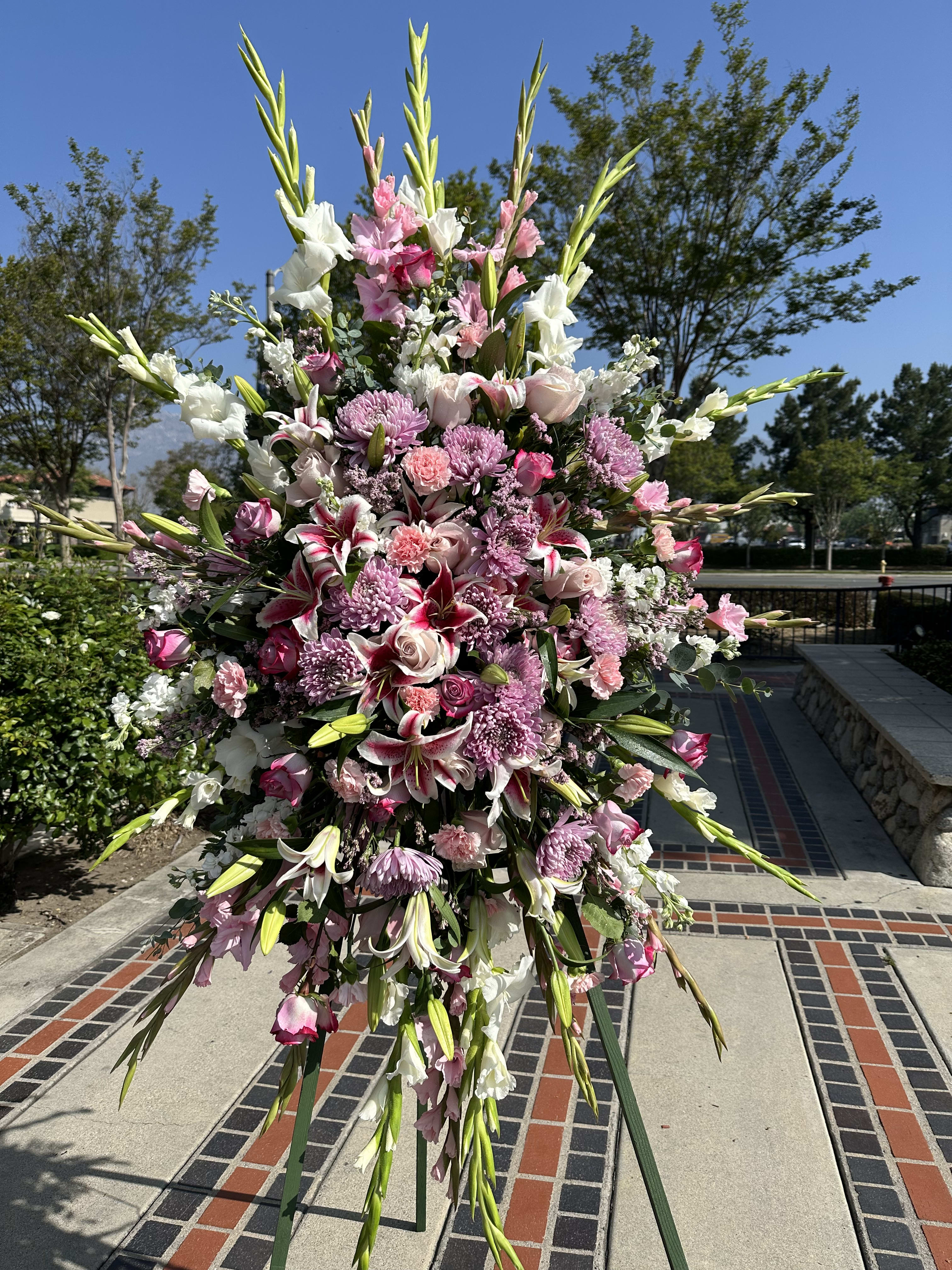 You’re in our thoughts and prayers - This is a large standing spray with purple lavender and white colored flowers Sortman of roses, carnations chrysanthemums Gladiolas. 