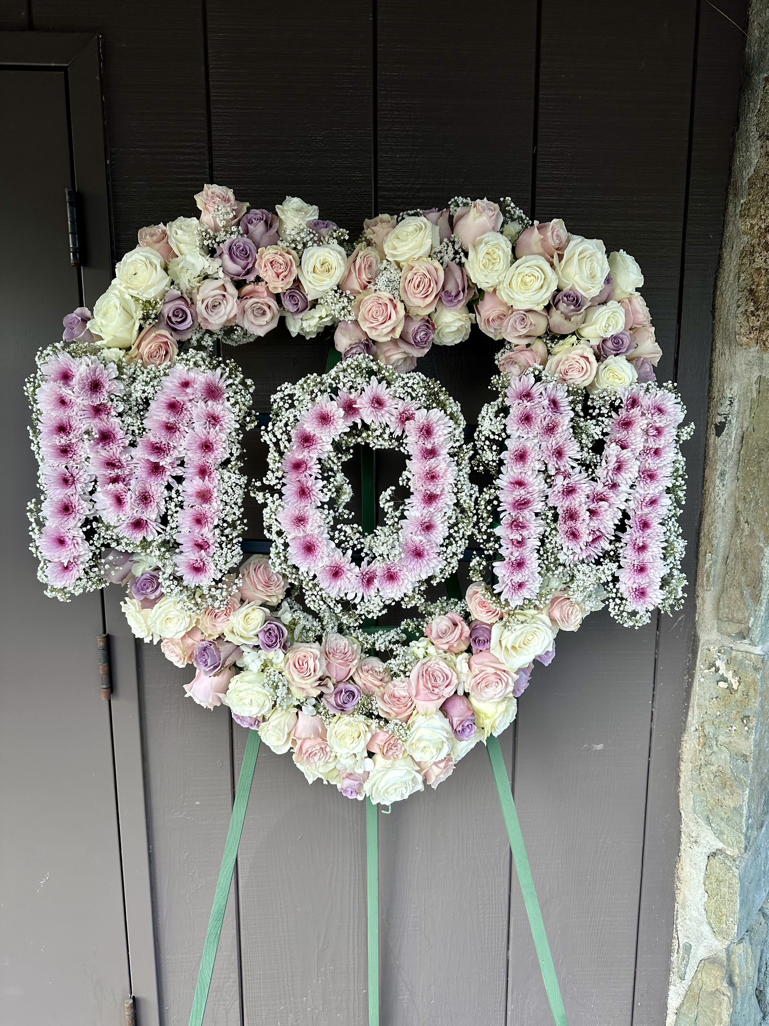 Mama  - Alway I our heart In the shape of a heart, and accented with mom in center designed with garden of delicate blooms is a tender and classic tribute to mothers precious life, and a cherished expression of love and sympathy. Beautiful flowers such as light pink roses, hydrangea and miniature carnations mix with lavender chrysanthemums on an open heart-shaped wreath. One-Sided