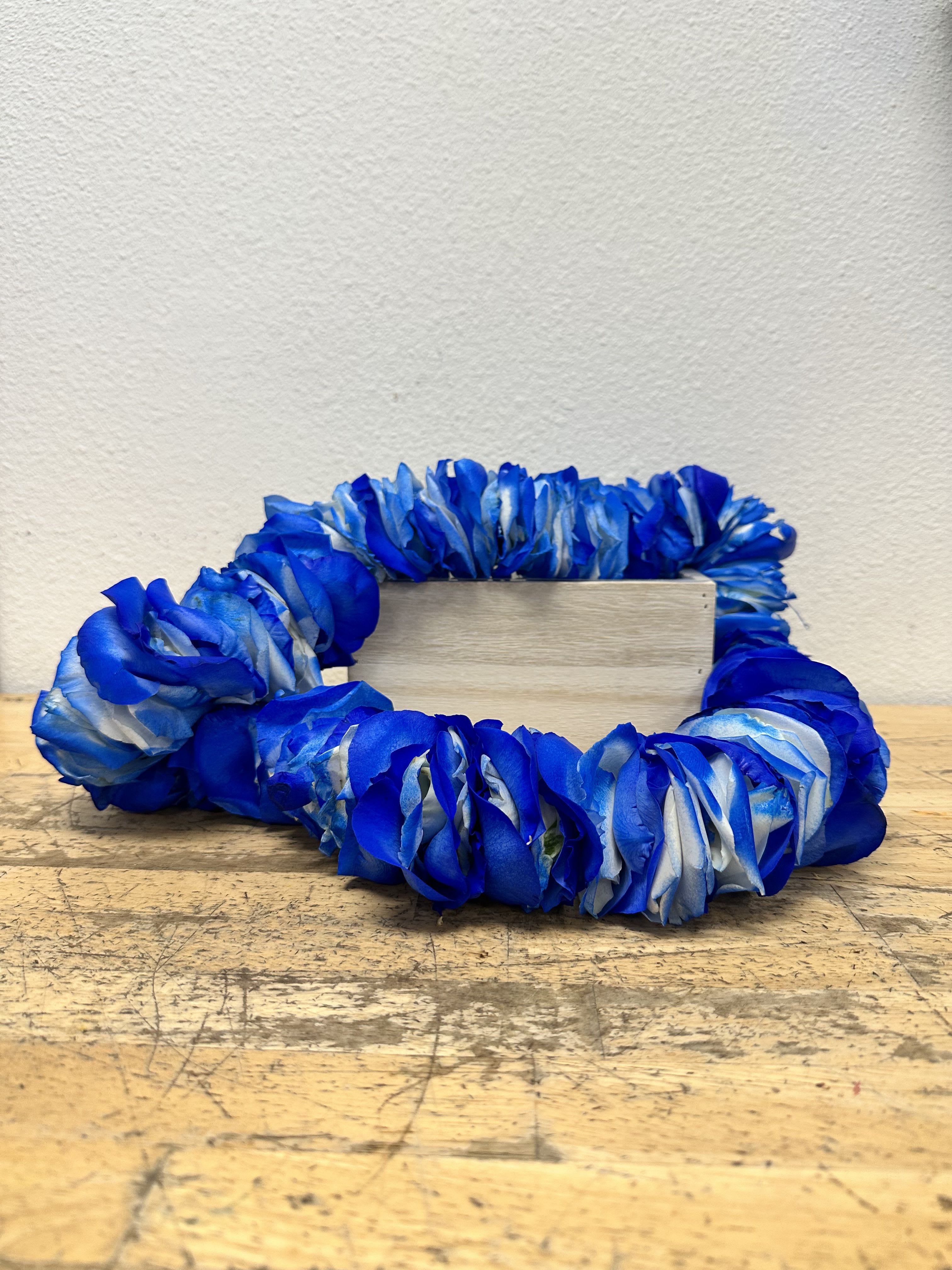 Blue floral wreath around a small wooden block