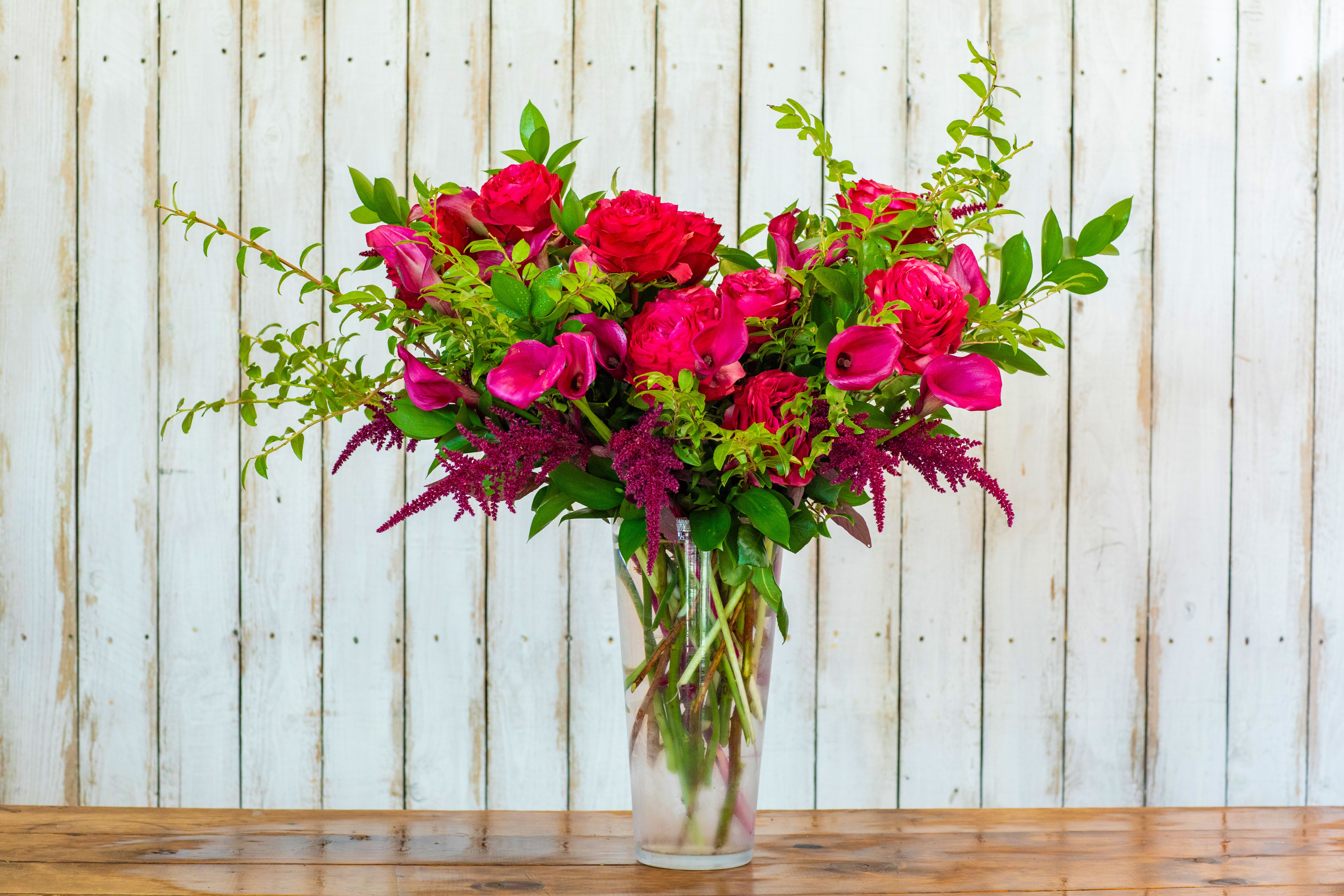 Pink roses and calla lilies in a clear glass vase