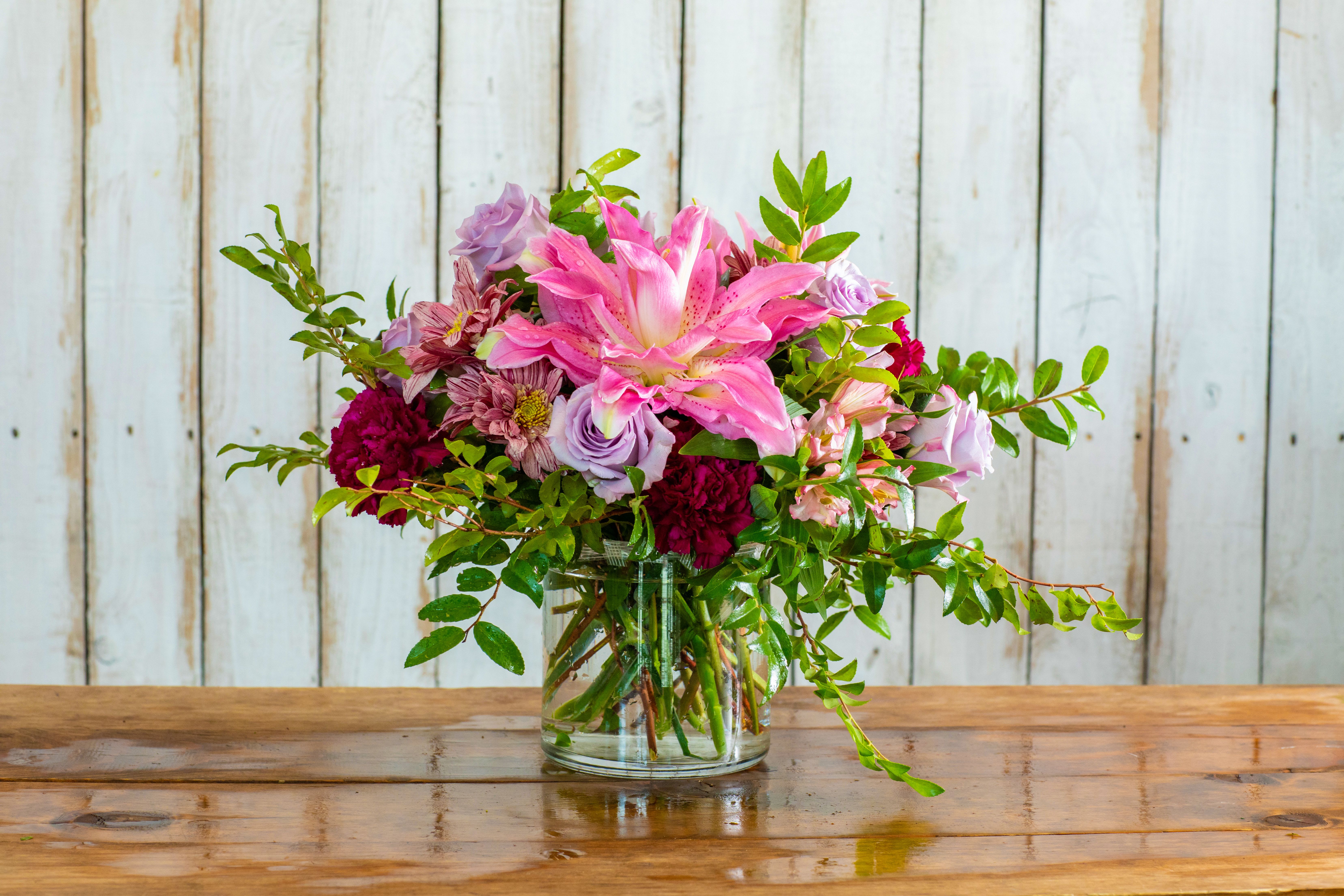 Lavender &amp; Pink Dream - Immerse yourself in elegance with the Lavender &amp; Pink Dream, a truly enchanting arrangement from your premier Rancho Cucamonga Florist. This luxurious bouquet is a romantic blend of soft lavenders and vibrant pinks, creating a dreamy and sophisticated display.  It features a striking pink stargazer lily as its focal point, surrounded by delicate lavender roses and deep burgundy mums. Accents of pink alstroemeria and rich green foliage add depth and texture, all artfully arranged in a classic clear glass vase, making it an exquisite gift to send instantly.  As the leading Rancho Cucamonga flower shop, we make it easy to shop online for flowers that express your deepest sentiments. This elegant arrangement is the perfect choice for a romantic anniversary gift, a heartfelt Mother's Day flowers surprise, a celebratory birthday bouquet, or thoughtful sympathy flowers.  We offer reliable same-day flower delivery throughout the entire Rancho Cucamonga area. Don't wait—order flowers now and trust our expertise to deliver a stunning and unforgettable arrangement. Buy flowers online today with confidence from your dependable local Rancho Cucamonga Florist!