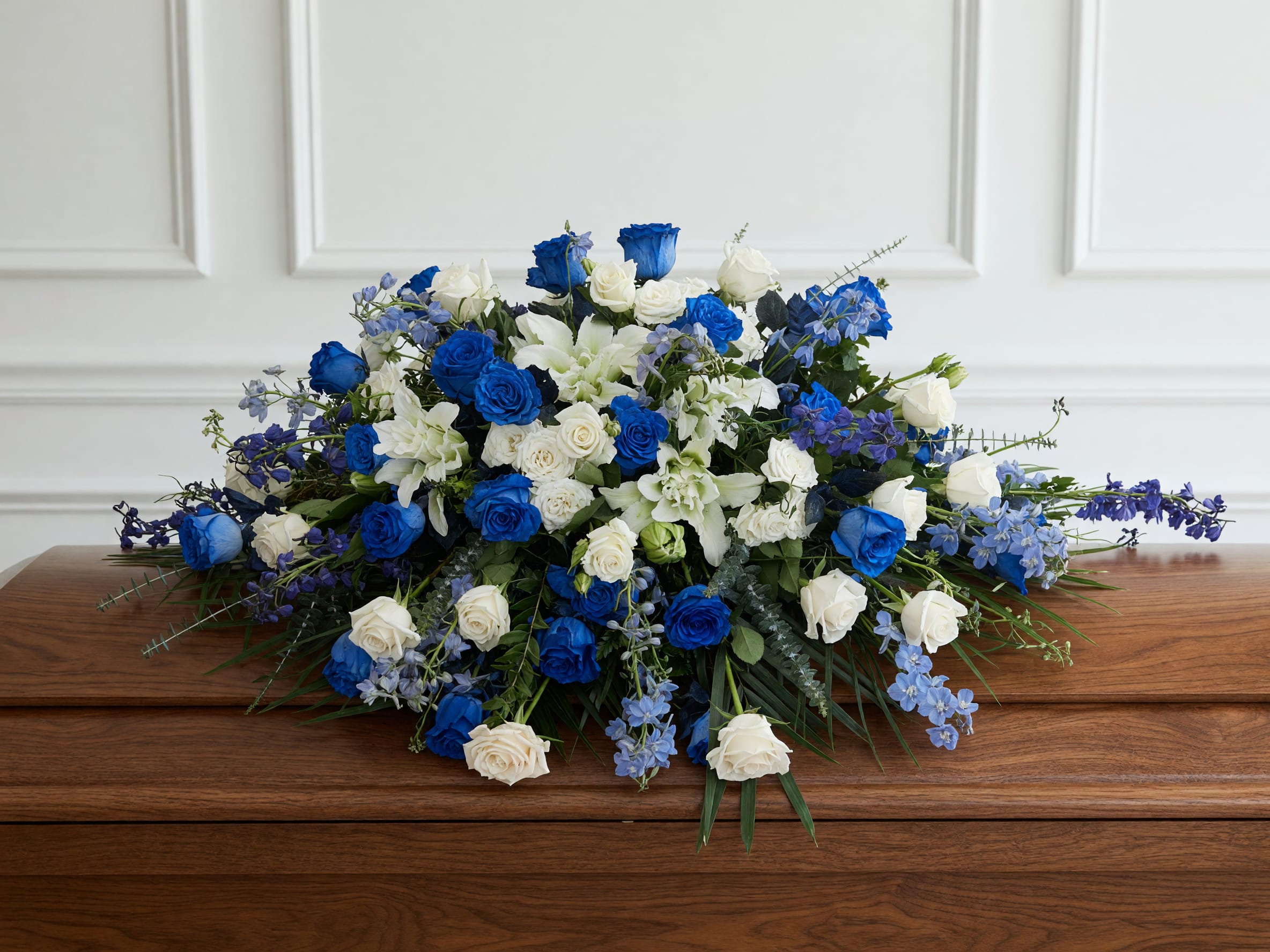 Heavenly Blue &amp; White Casket Spray - Celebrate a beautiful life with our Heavenly Blue &amp; White Casket Spray, a luxurious funeral flower arrangement handcrafted by the designers at Tommy Austin Florist in Rancho Cucamonga. Featuring vibrant blue roses, elegant white roses, fragrant white lilies, blue delphinium, and fresh greenery, this full casket spray creates a peaceful and meaningful tribute. Perfect for funeral services, memorial services, and celebrations of life, this arrangement is carefully designed to express love, honor, and remembrance. We proudly deliver funeral flowers throughout Rancho Cucamonga, Ontario, Upland, Fontana, Claremont, La Verne, Montclair, Pomona, Eastvale, and surrounding Southern California communities.