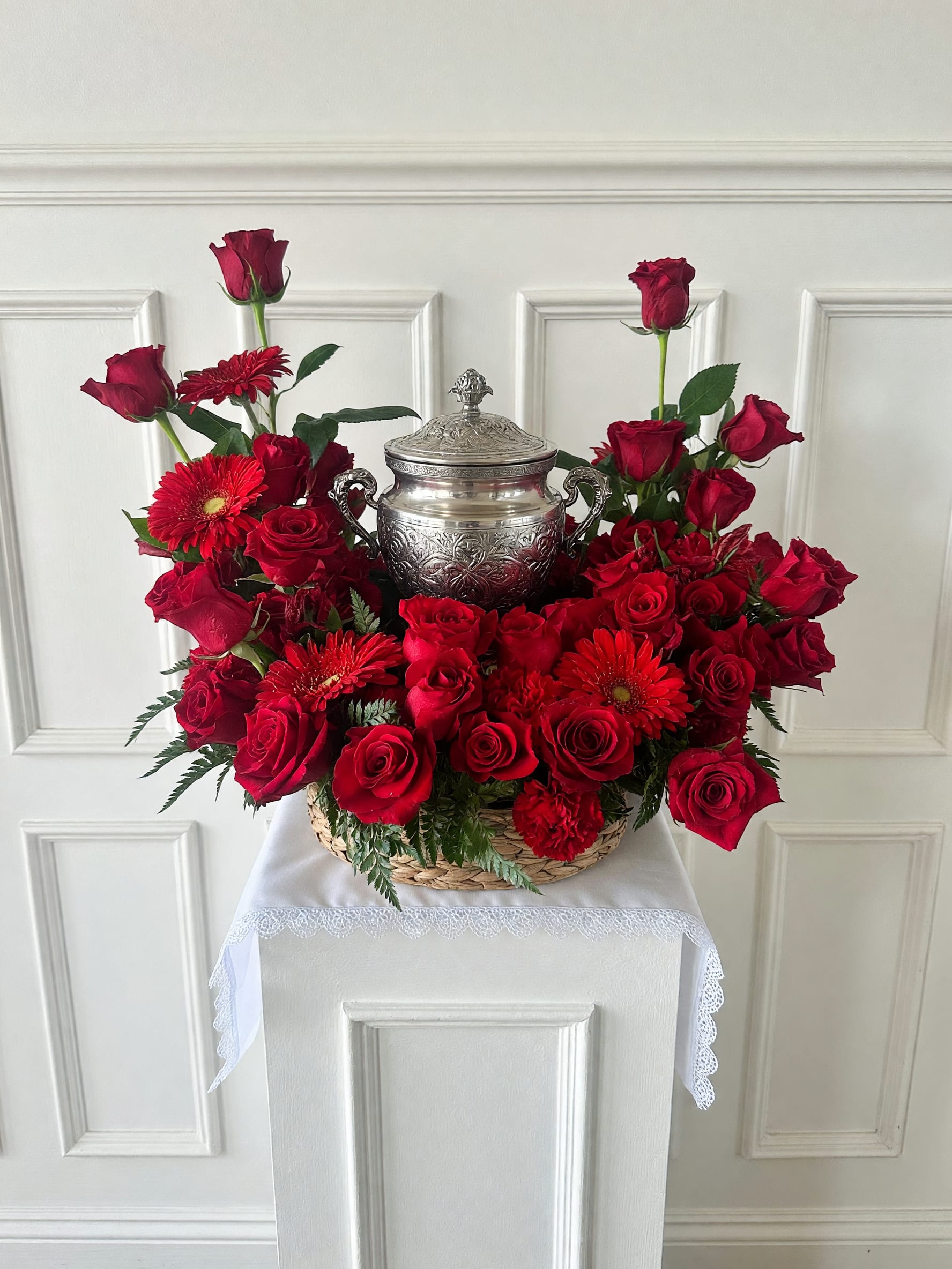 Crimson Remembrance Urn Tribute - Celebrate a cherished life with our Crimson Remembrance Urn Tribute, a stunning sympathy arrangement handcrafted by Tommy Austin Florist in Rancho Cucamonga. This elegant design features premium red roses, red gerbera daisies, carnations, and lush seasonal greenery, creating a heartfelt display of love, honor, and remembrance. Designed to beautifully frame a cremation urn, this arrangement is ideal for funeral services, memorials, celebrations of life, churches, mortuaries, and family gatherings. Each tribute is thoughtfully created by our experienced floral designers using the freshest flowers available. We proudly deliver sympathy flowers throughout Rancho Cucamonga, Ontario, Upland, Fontana, Claremont, La Verne, Montclair, Pomona, Eastvale, and surrounding Inland Empire communities.  Please Note: Urn is shown for display purposes only and is not included unless otherwise specified 