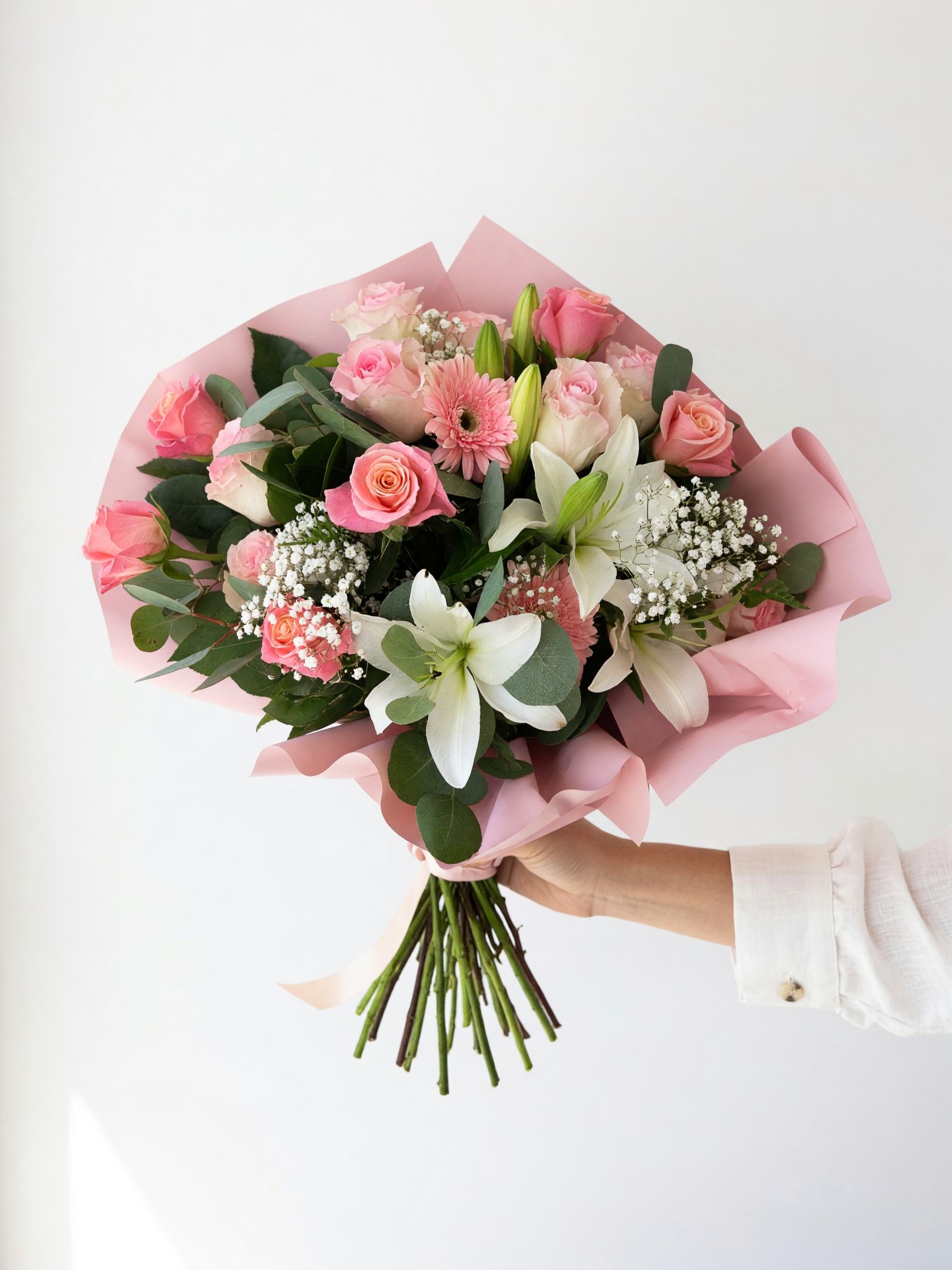 Pink and white mixed bouquet with roses, lilies, and gerbera daisies wrapped in pink paper