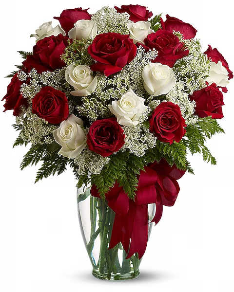 Red and white roses arranged in a clear glass vase with a red ribbon