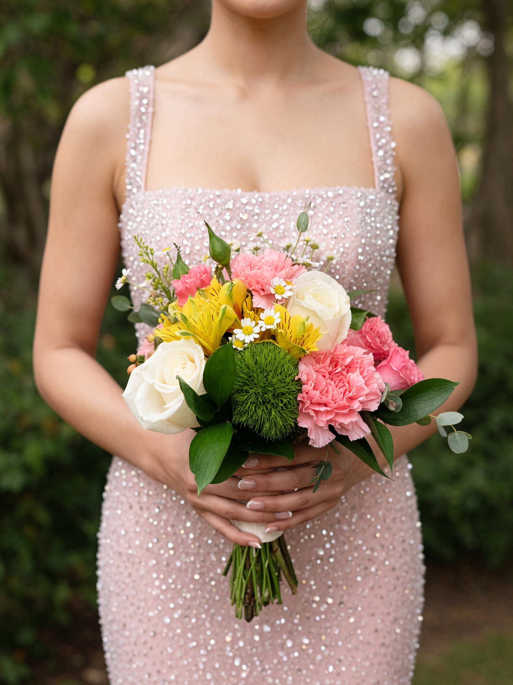 Spring Nosegay  - A compact hand-tied Spring Nosegay designed to make someone feel cherished the moment they see it - perfect as a birthday bouquet, wedding gift, or a thoughtful arrangement to say "I'm thinking of you." The rounded, bridal-inspired silhouette pairs creamy white roses with soft pink carnations and sunny yellow alstroemeria so the recipient will feel both celebrated and comforted by its fresh garden charm.  The bouquet also includes delicate daisy accents and lush green foliage for texture and contrast, all arranged in a neat, wrapped stem bundle that's easy to display in a vase. Soft pink, white, yellow, and green tones blend for a cheerful yet romantic palette that photographs beautifully and suits springtime events or intimate celebrations.  Send this nosegay when you want someone to feel noticed - for anniversaries, bridal showers, or simply to brighten a day. Stems arrive ready to trim and place in water; replace water daily and recut stems every few days to keep the arrangement looking fresh.