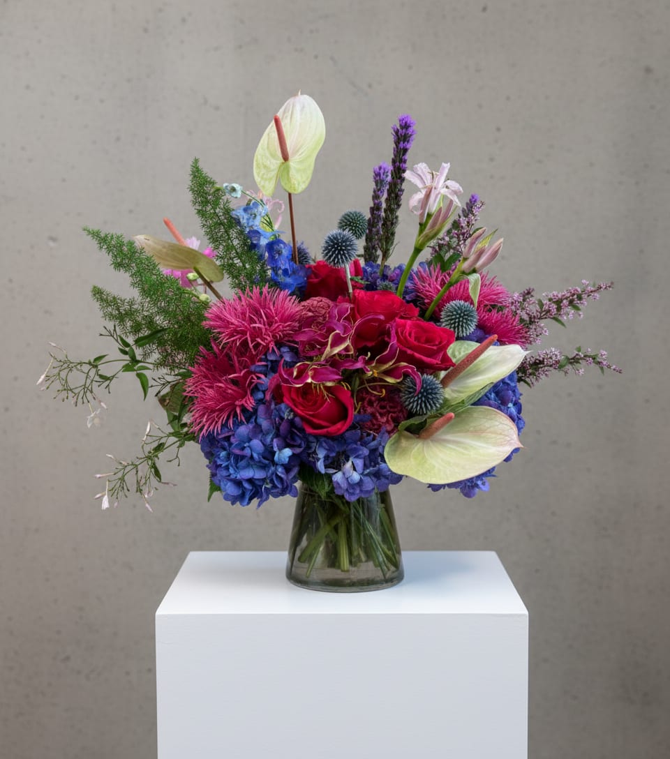 Colorful mixed bouquet in a glass vase with roses, hydrangeas, and anthuriums
