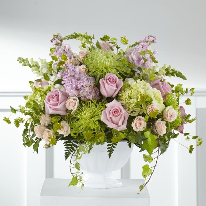 Pink roses and green blooms arranged in a white vase