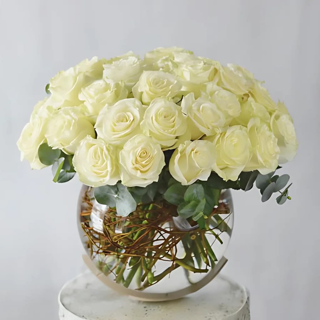 Round bouquet of cream roses in a clear glass vase