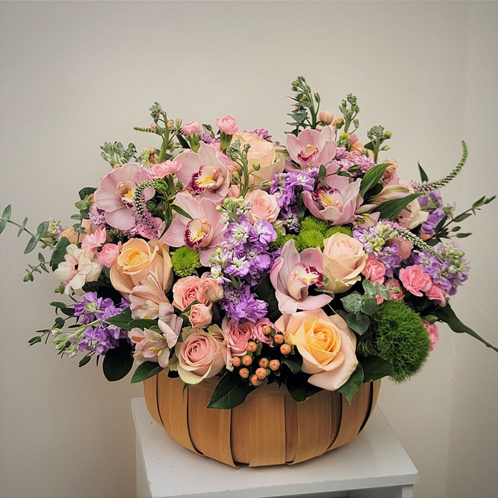 Large pastel flower arrangement in a wooden basket
