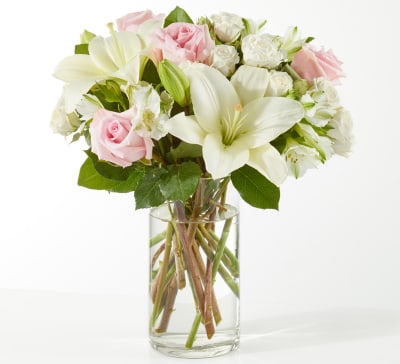 Pink roses and white lilies arranged in a clear glass vase