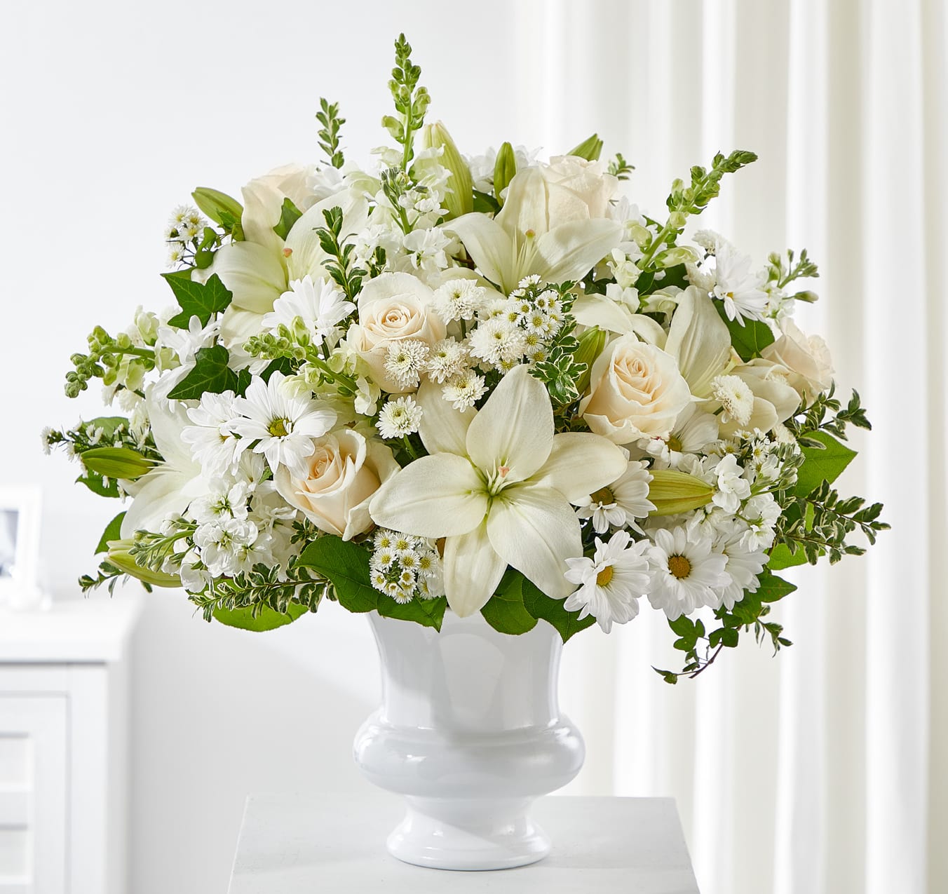 White lilies and roses arranged in a white vase