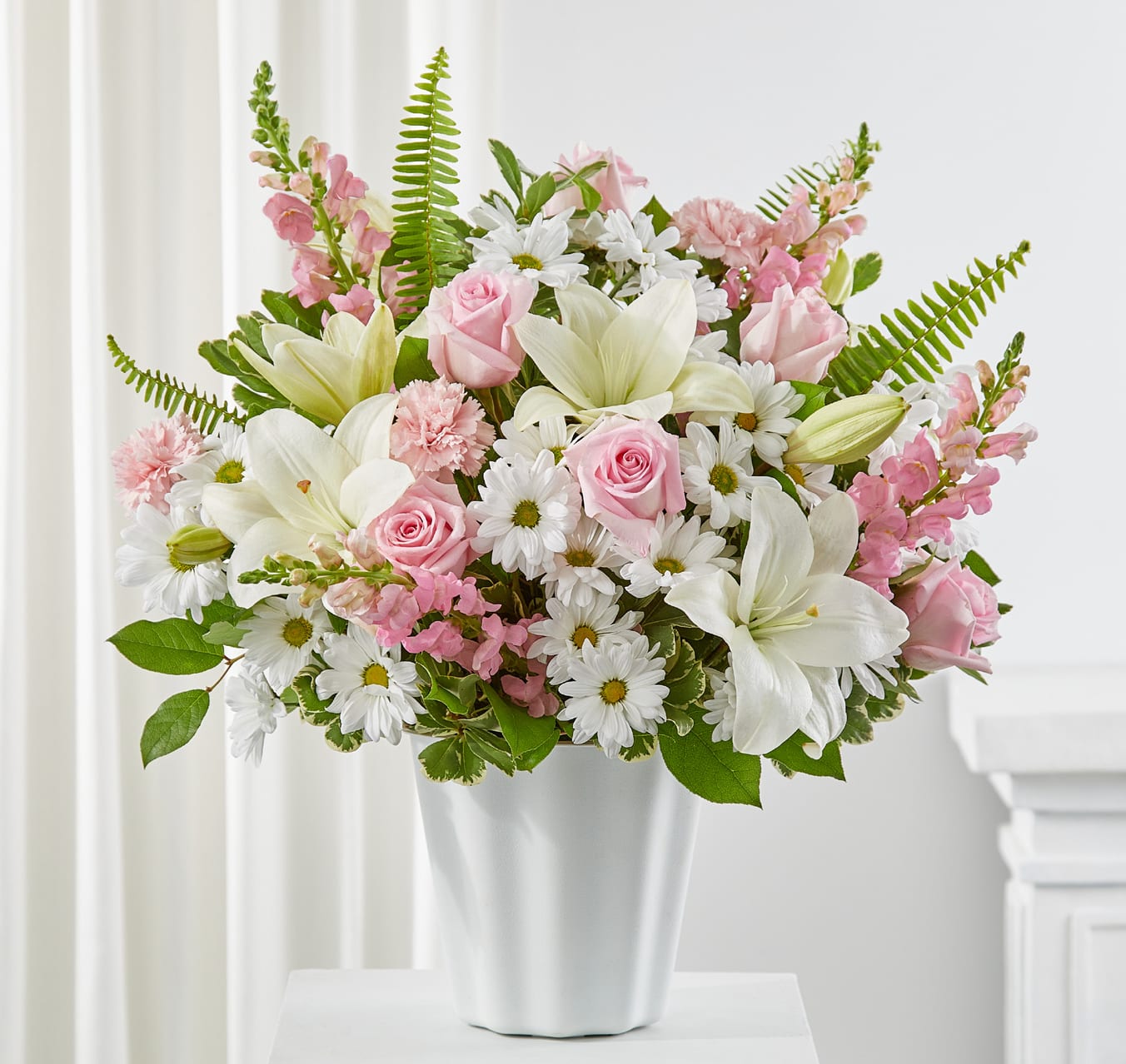 Pink roses and white lilies arranged in a white vase