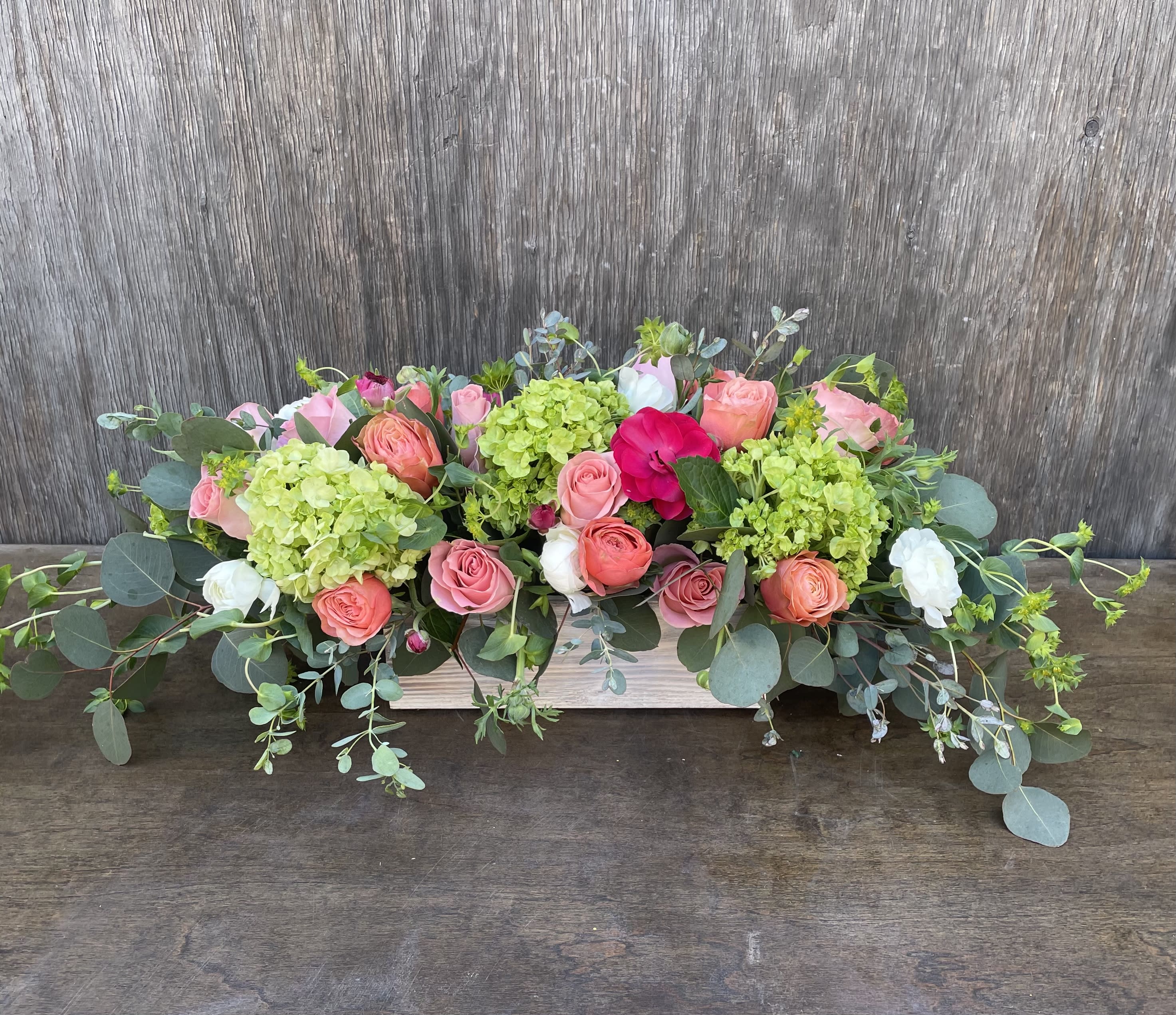 Low floral centerpiece with pink and coral roses and green hydrangeas