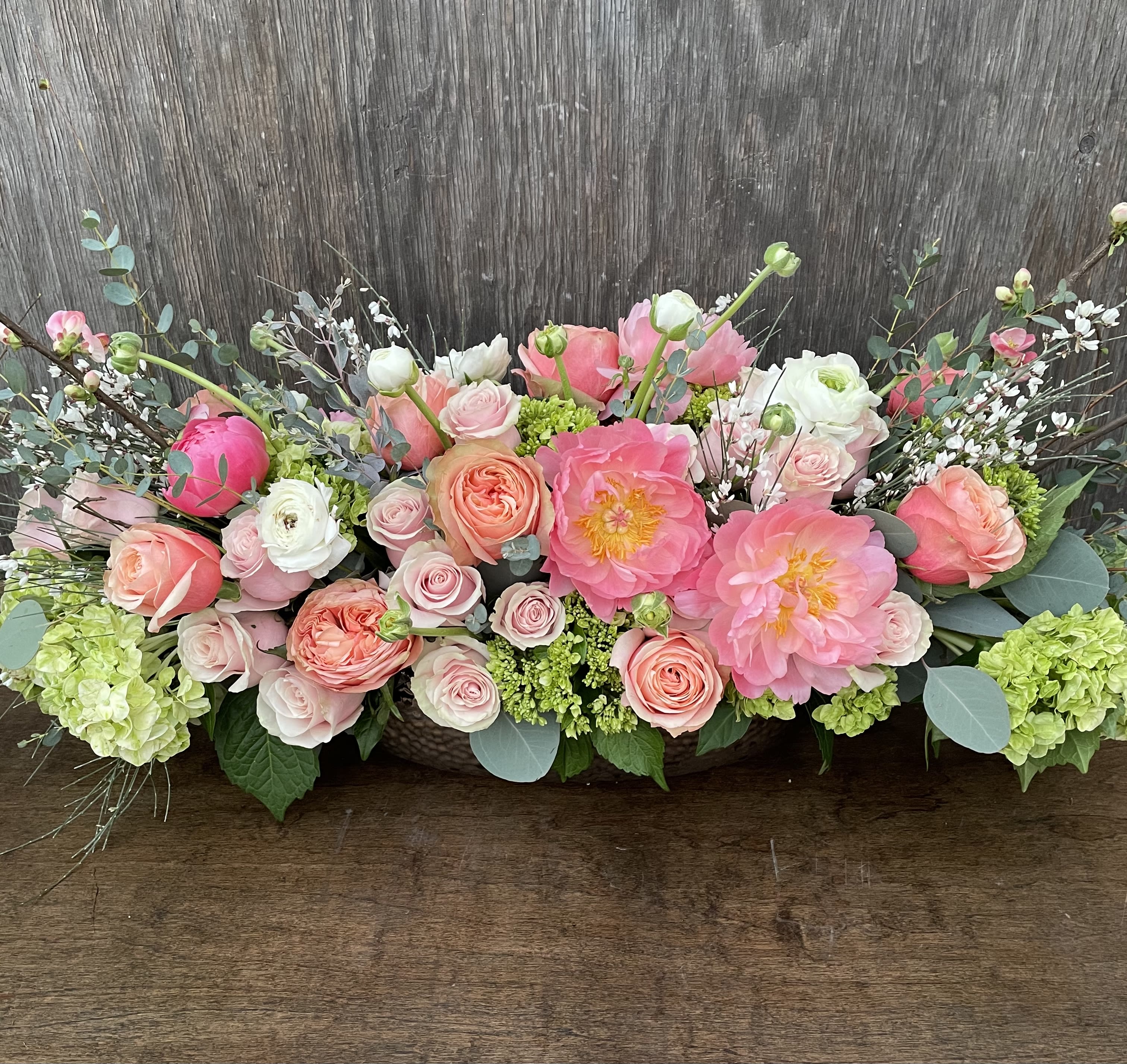 Low floral arrangement of pink and peach roses with large pink blooms