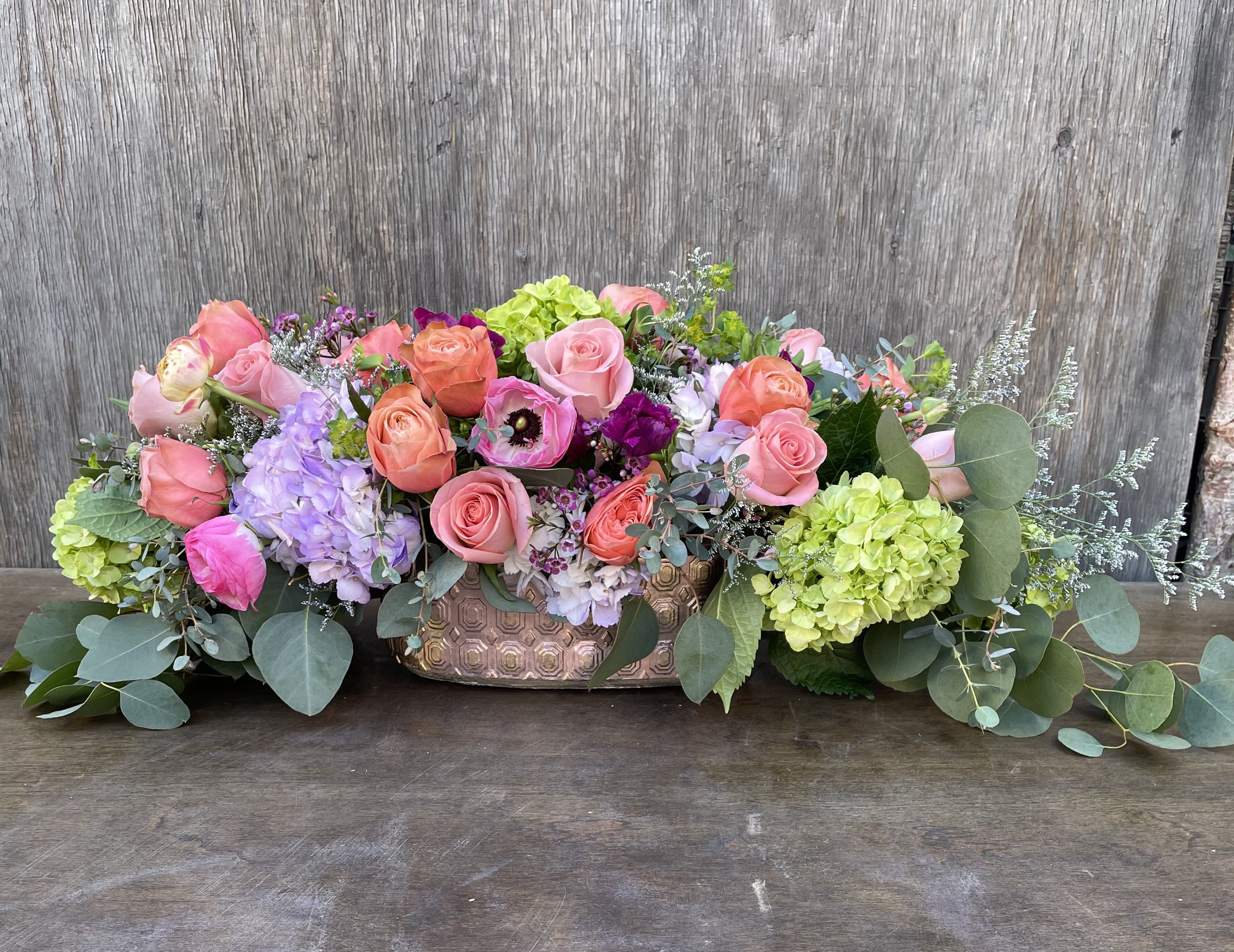 Low floral centerpiece with pink and coral roses in a copper vase