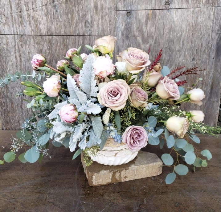 Blush roses and buds arranged in a white bowl vase