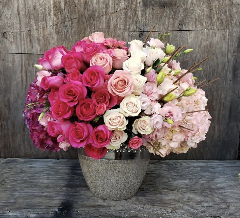 Pink and white roses with pale hydrangeas in a gray vase