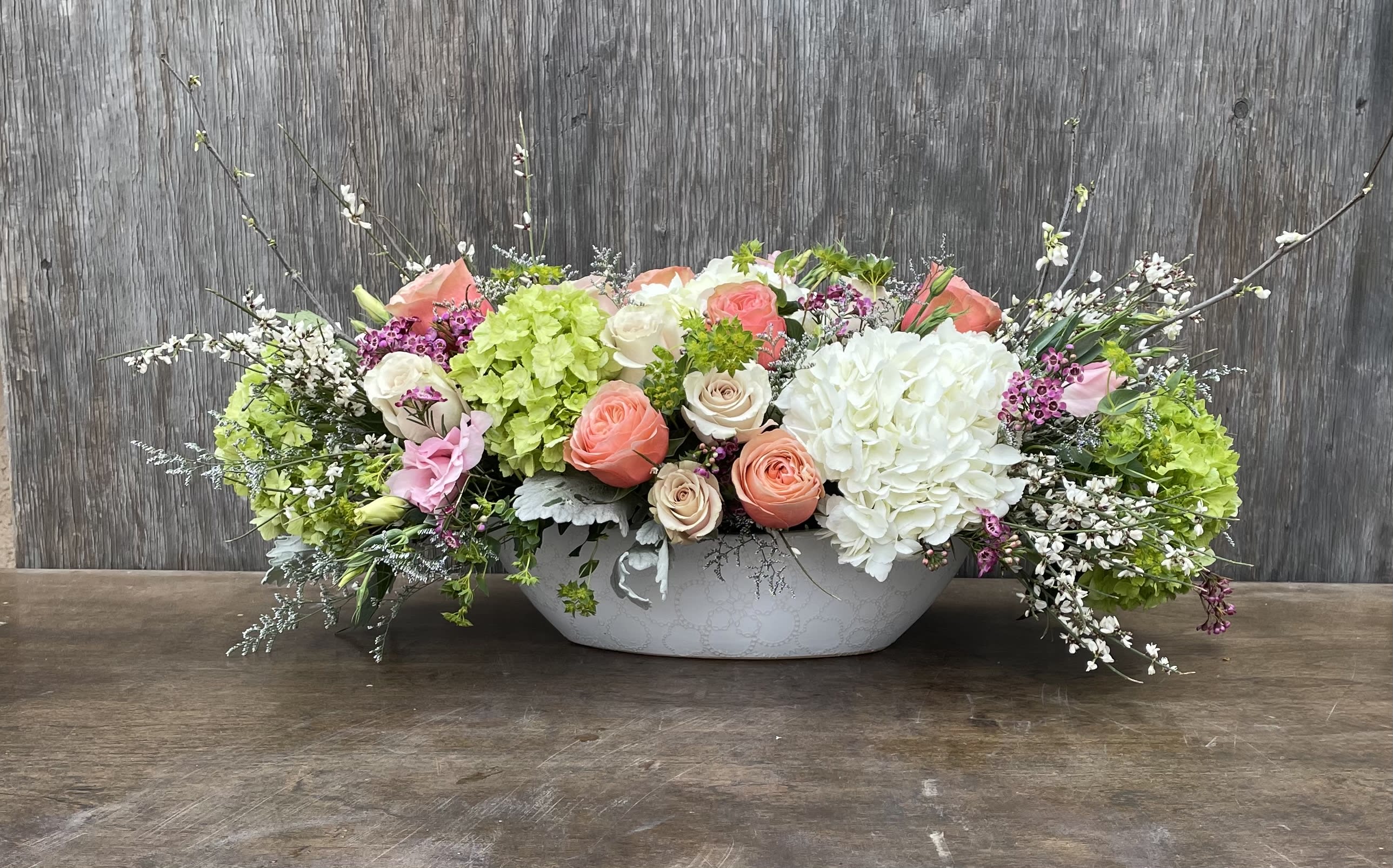 Low floral centerpiece with pink and white roses in a white container
