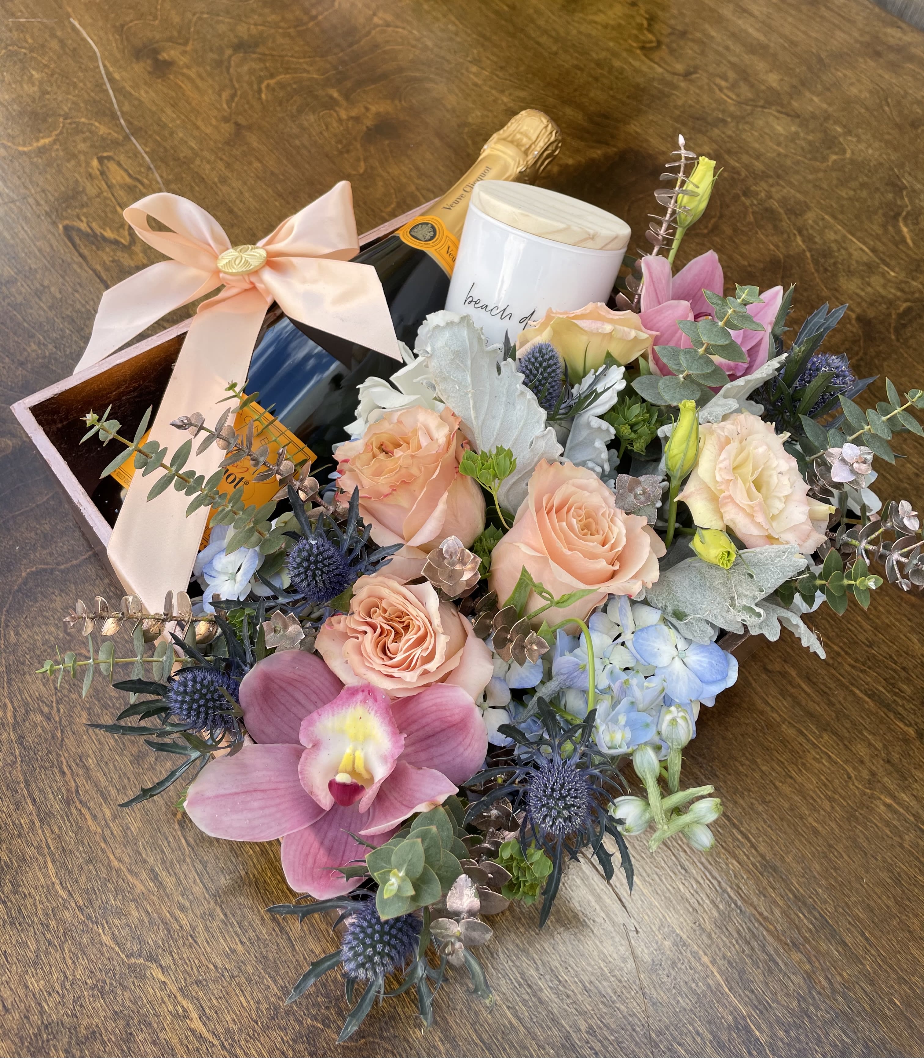 Bouquet with roses, orchids, and a champagne bottle in a gift box