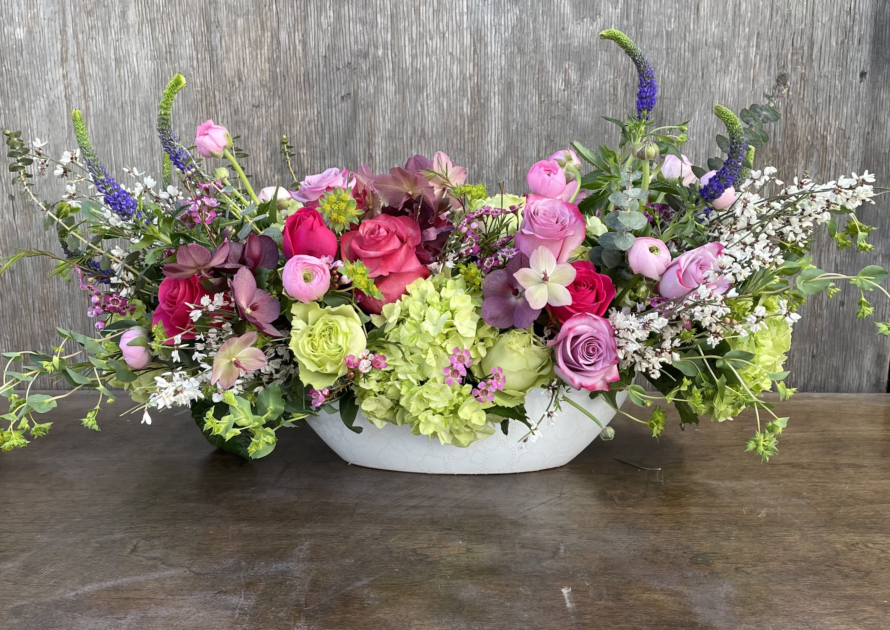 Low floral centerpiece with pink and purple roses in a white bowl vase