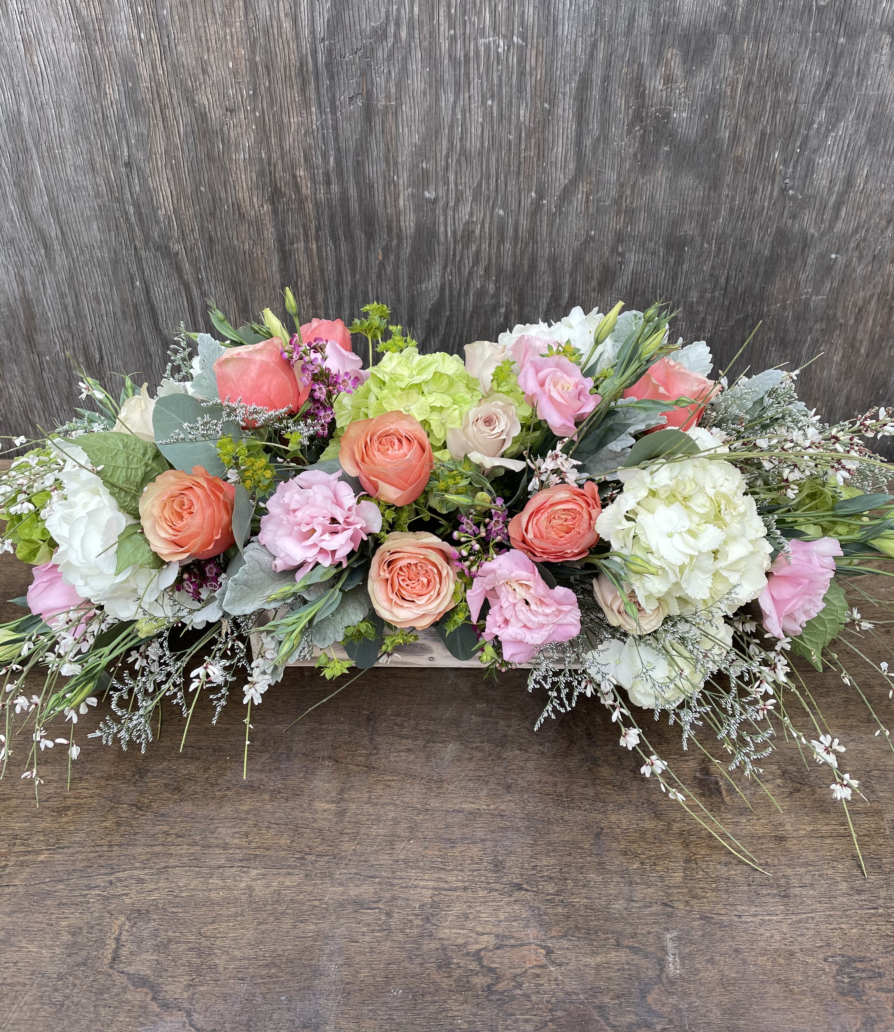 Low floral arrangement with pink, peach, and white blooms