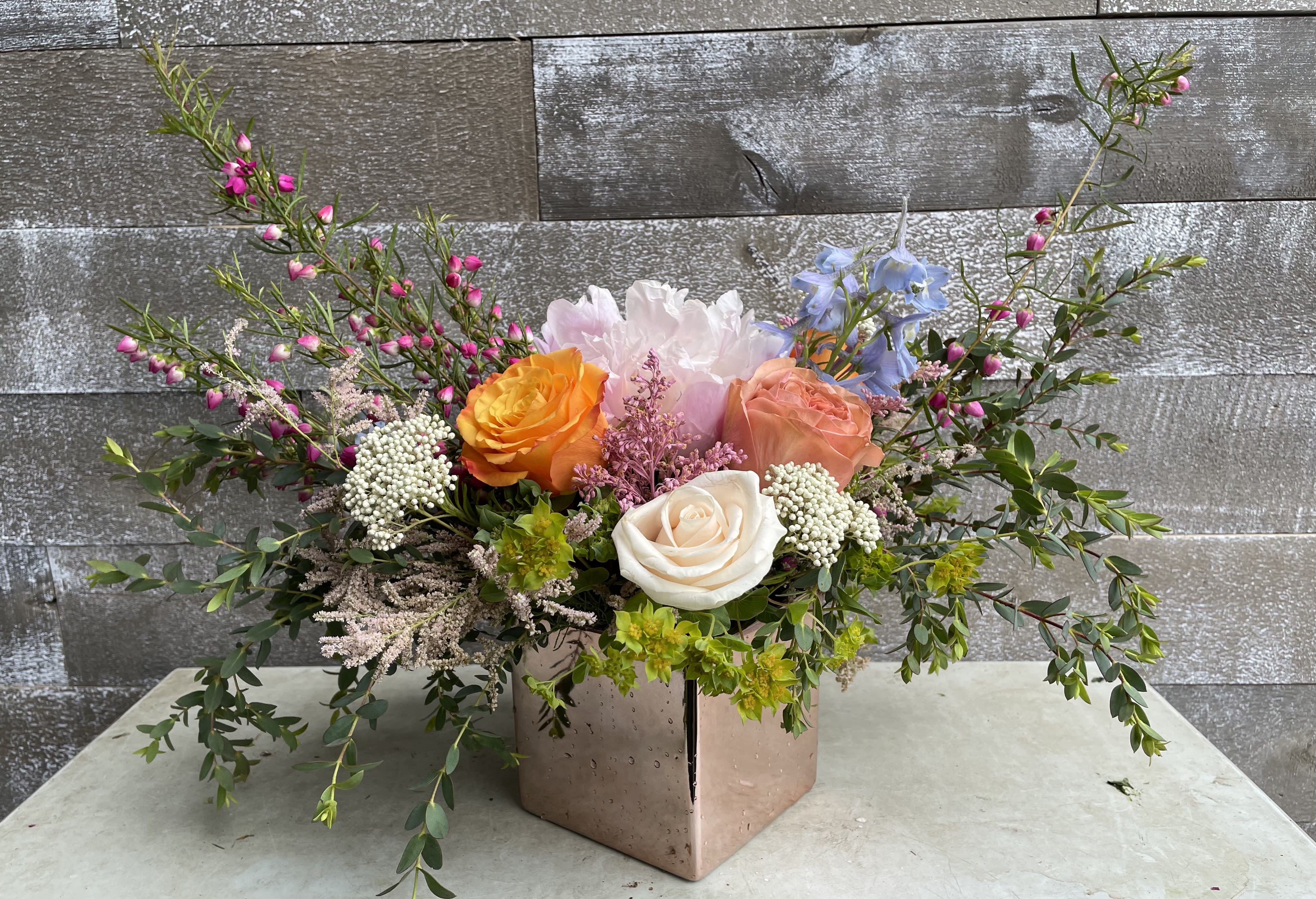 Mixed bouquet with roses and pastel blooms in a square vase