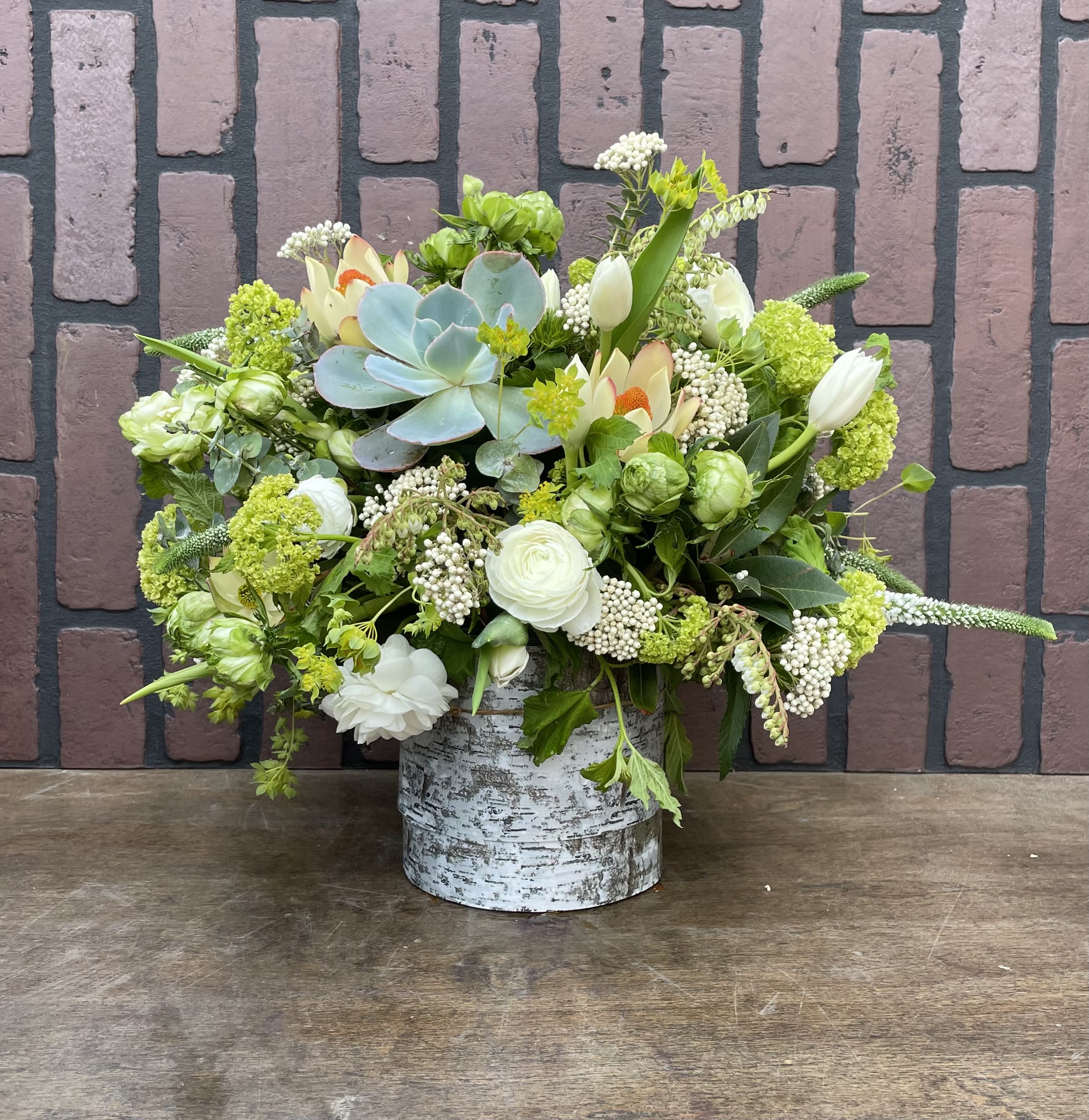 Mixed floral arrangement in a birch-style container with a blue succulent centerpiece