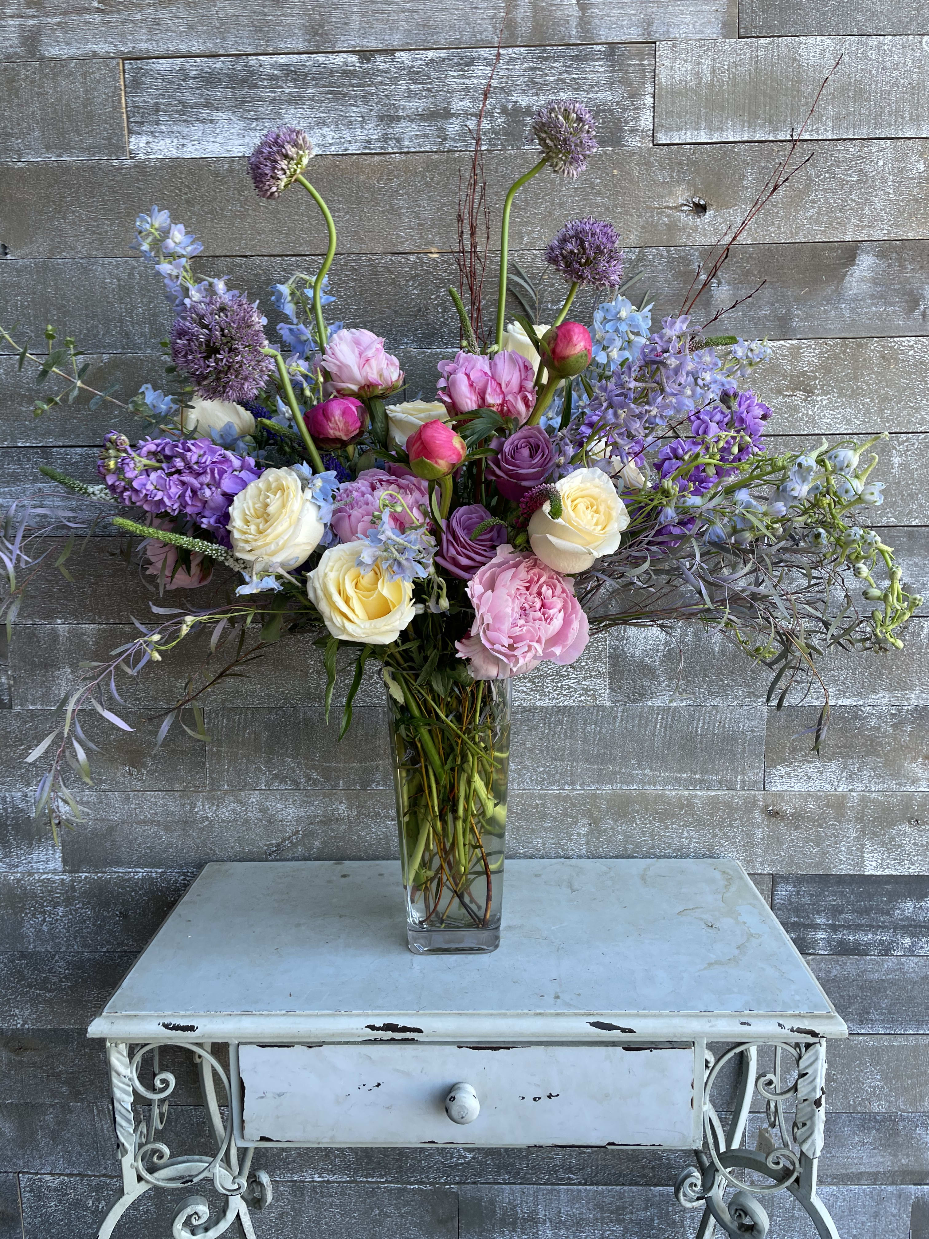 Tall mixed bouquet in a clear glass vase with pink, purple, and white blooms