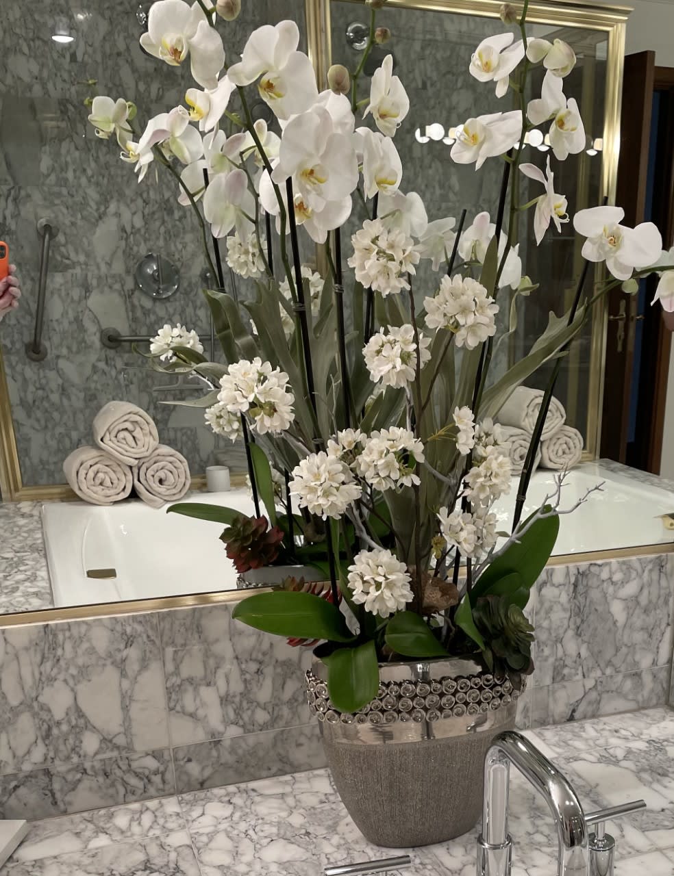 Tall white orchid arrangement in a decorative silver vase