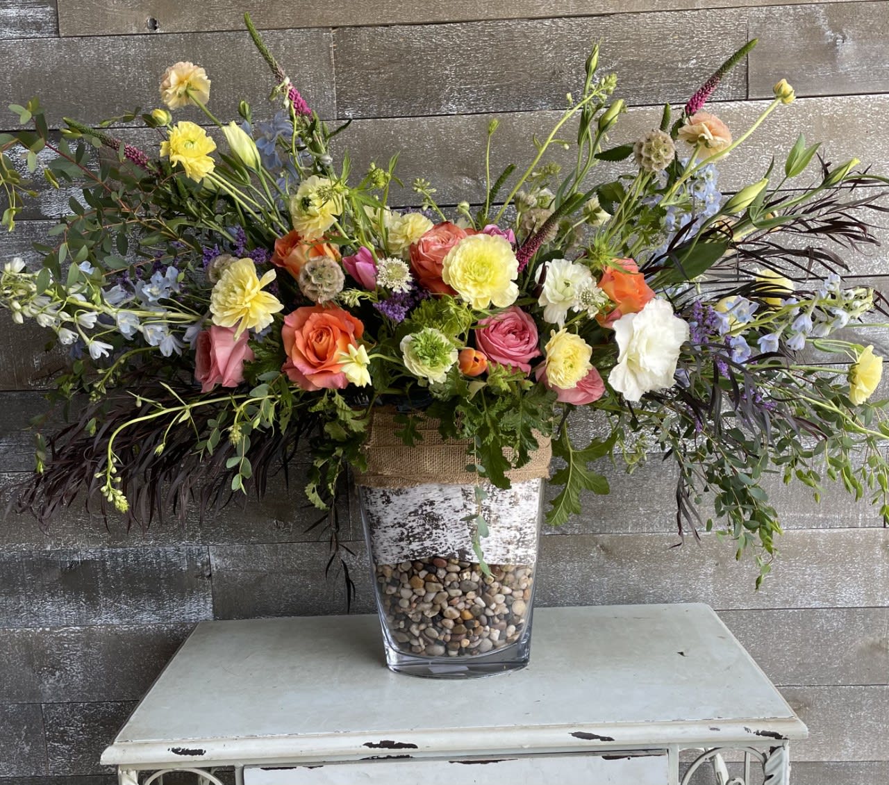 Large mixed floral arrangement in a clear vase with pebbles