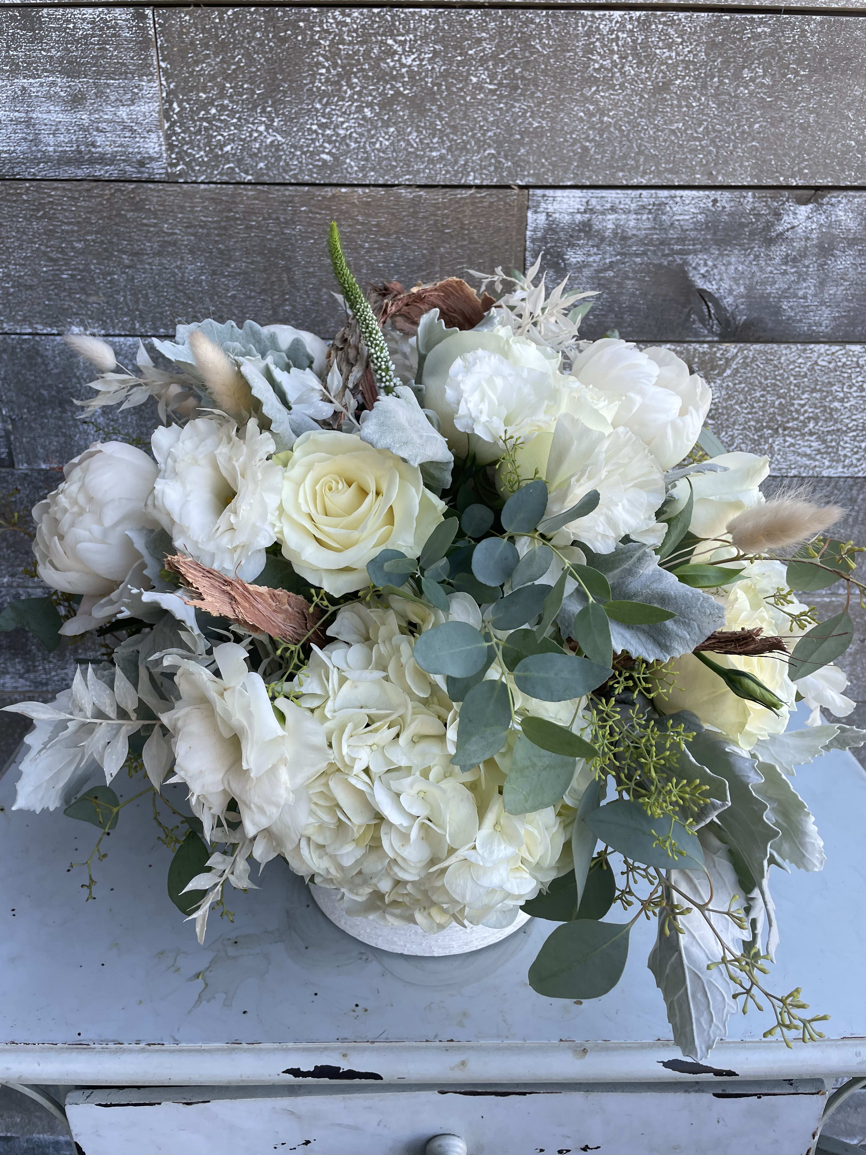 White floral bouquet in a low white container with eucalyptus