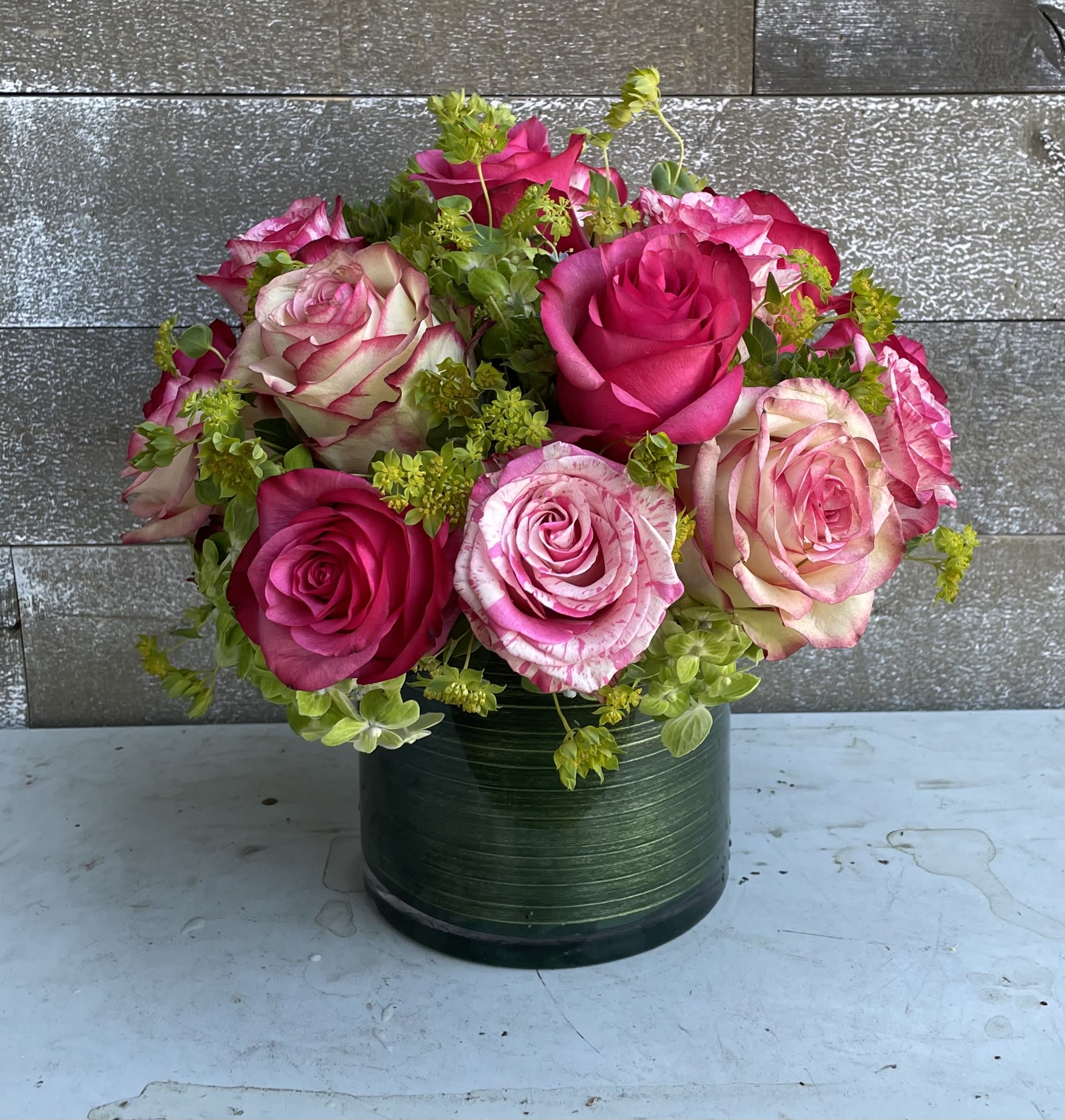 Pink and cream roses arranged in a green round vase