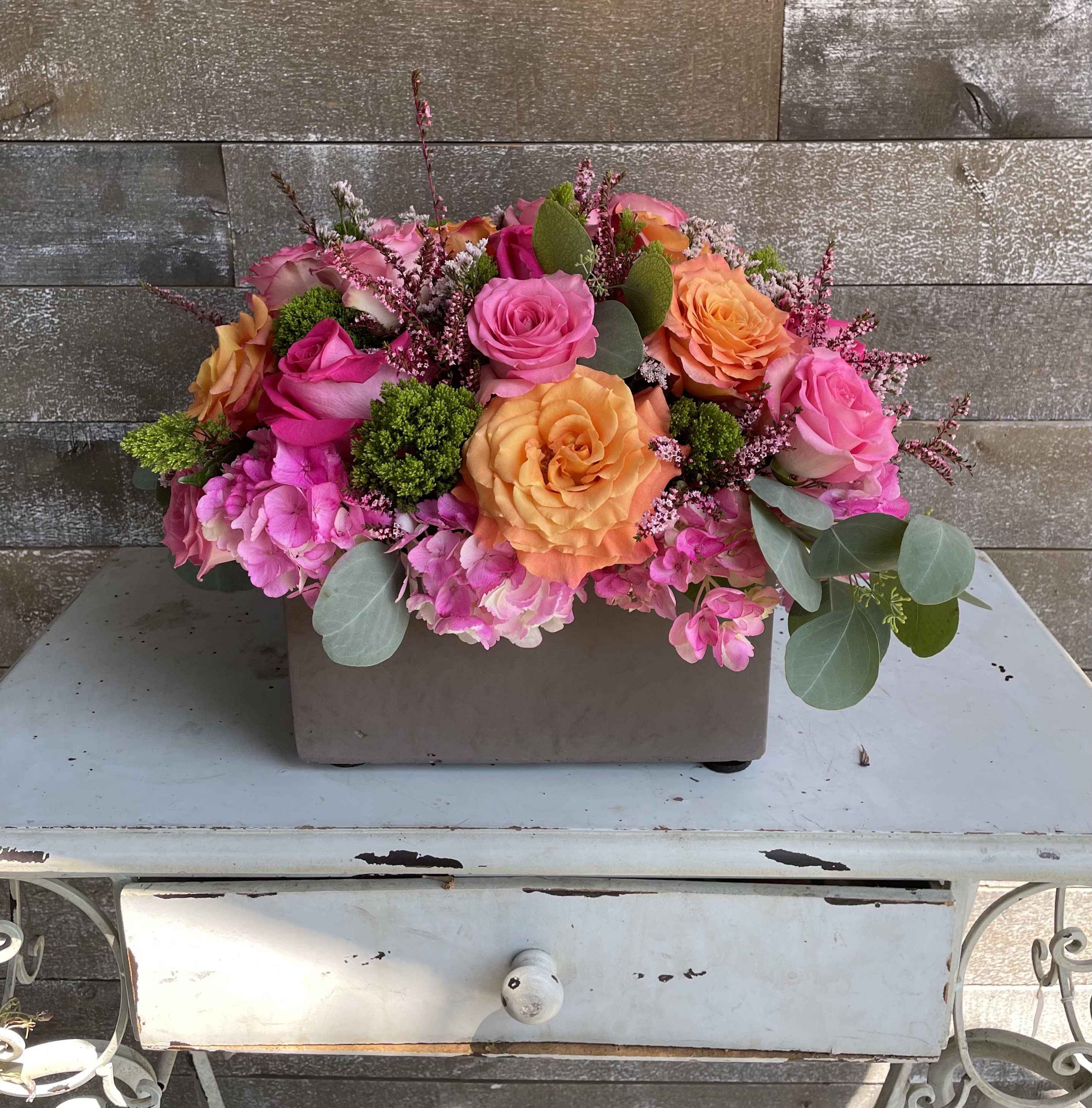 Pink and orange rose arrangement in a rectangular container