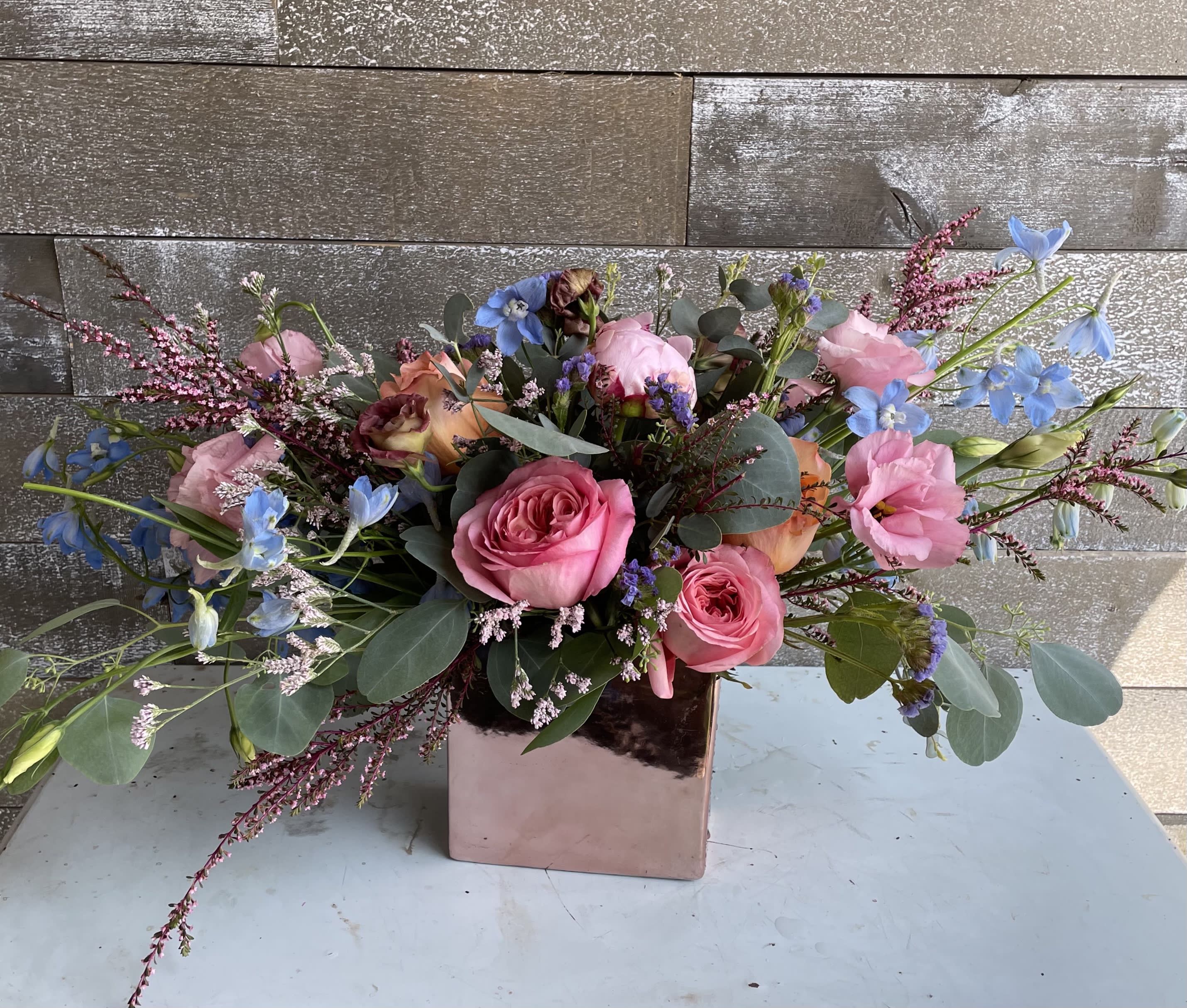 Pink roses and blue flowers in a square metallic vase