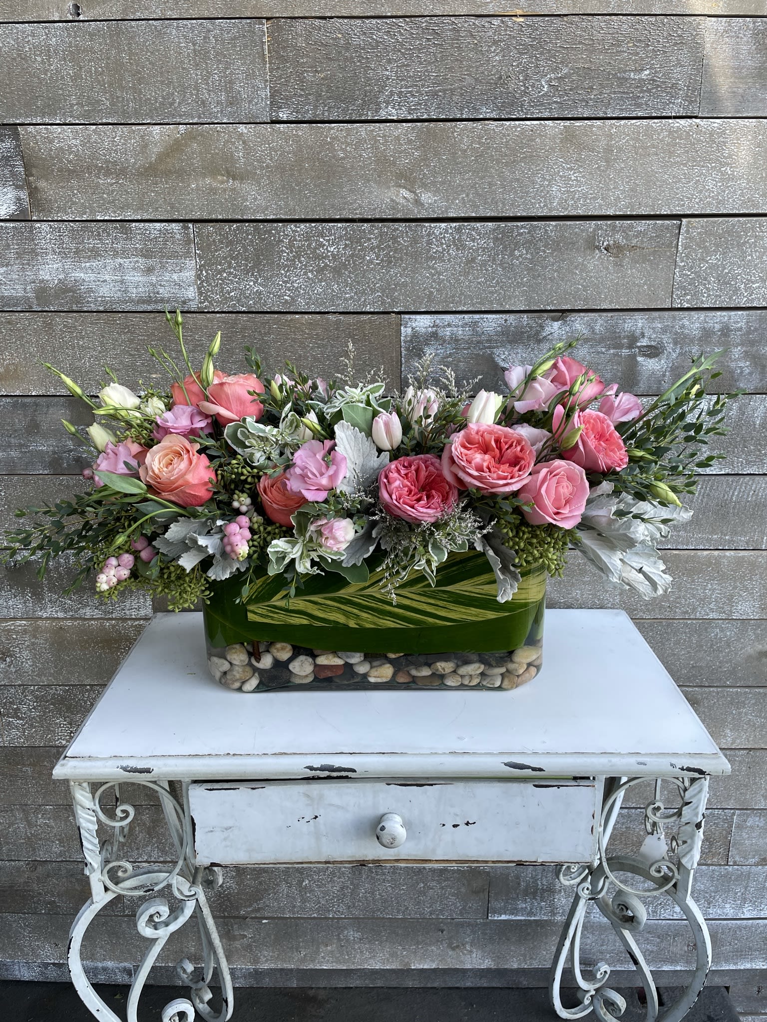 Pink and peach roses arranged in a rectangular glass vase