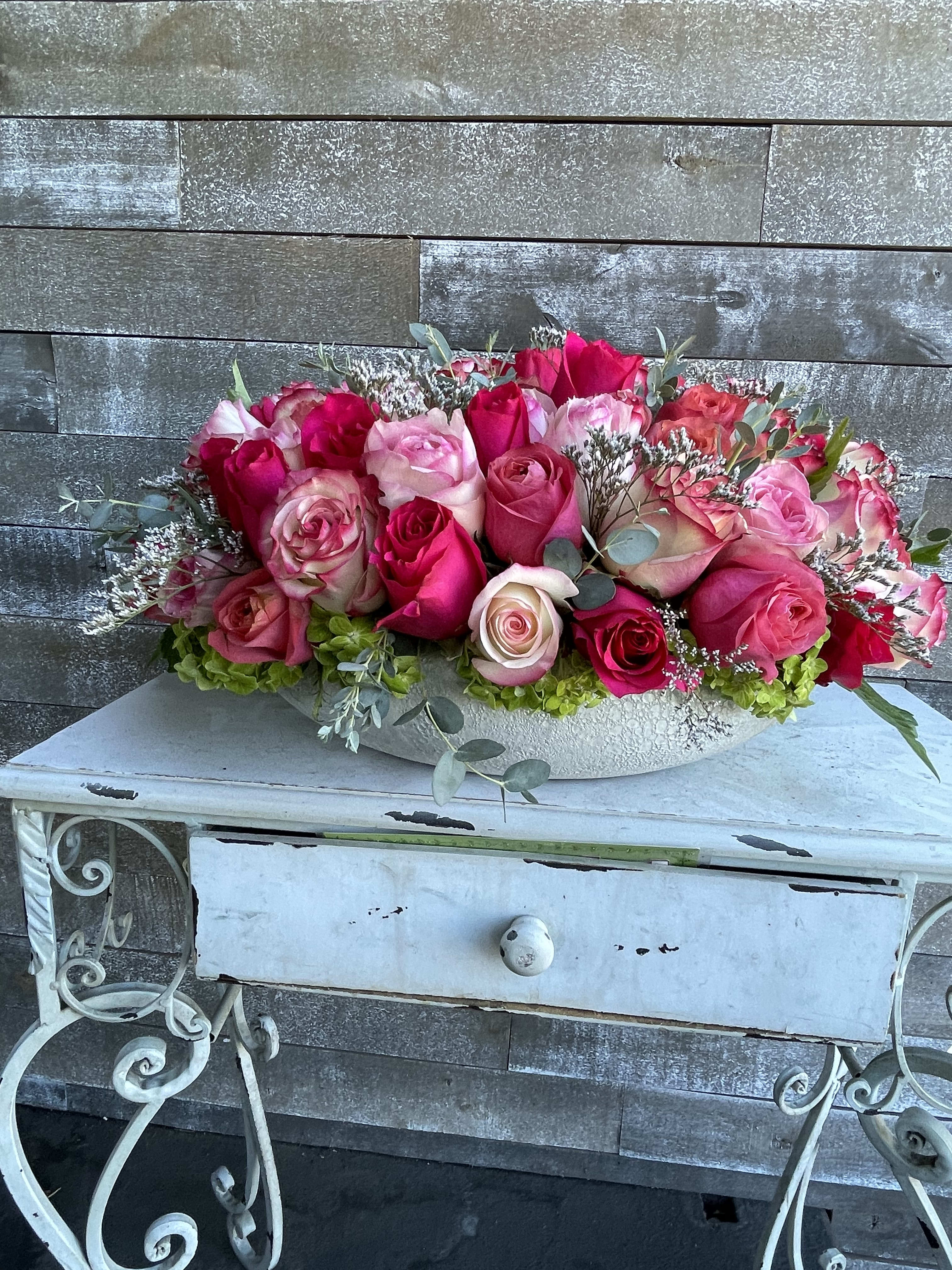 Pink and red rose arrangement in a white bowl vase