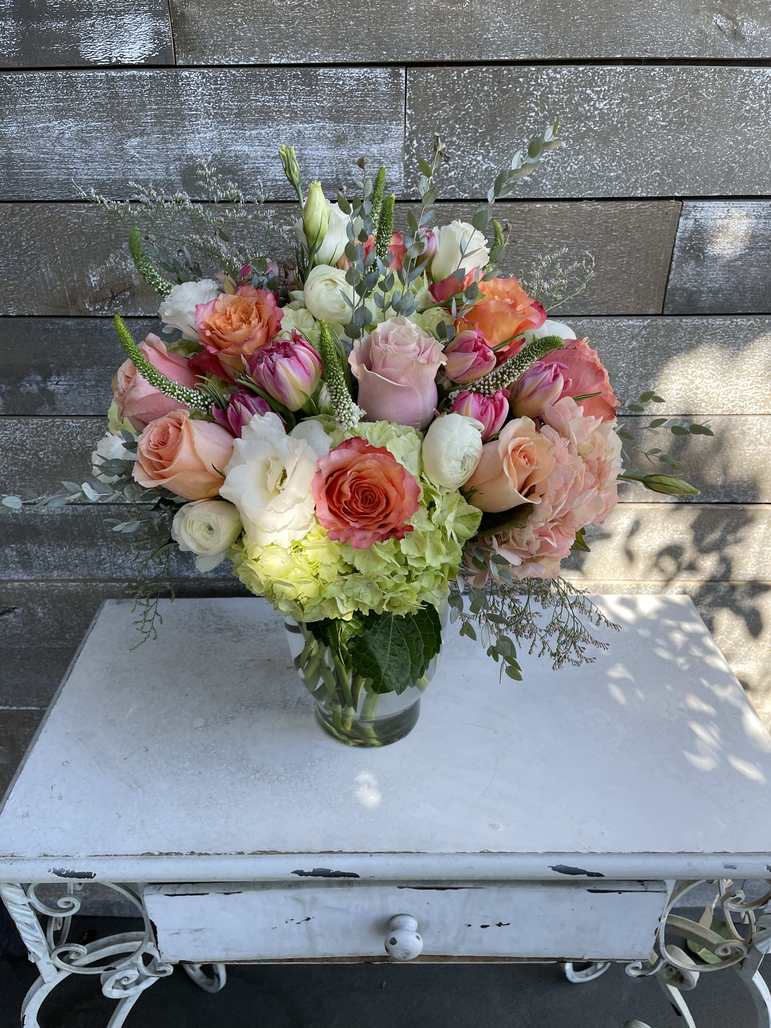 Mixed bouquet of roses, tulips, and hydrangeas in a glass vase