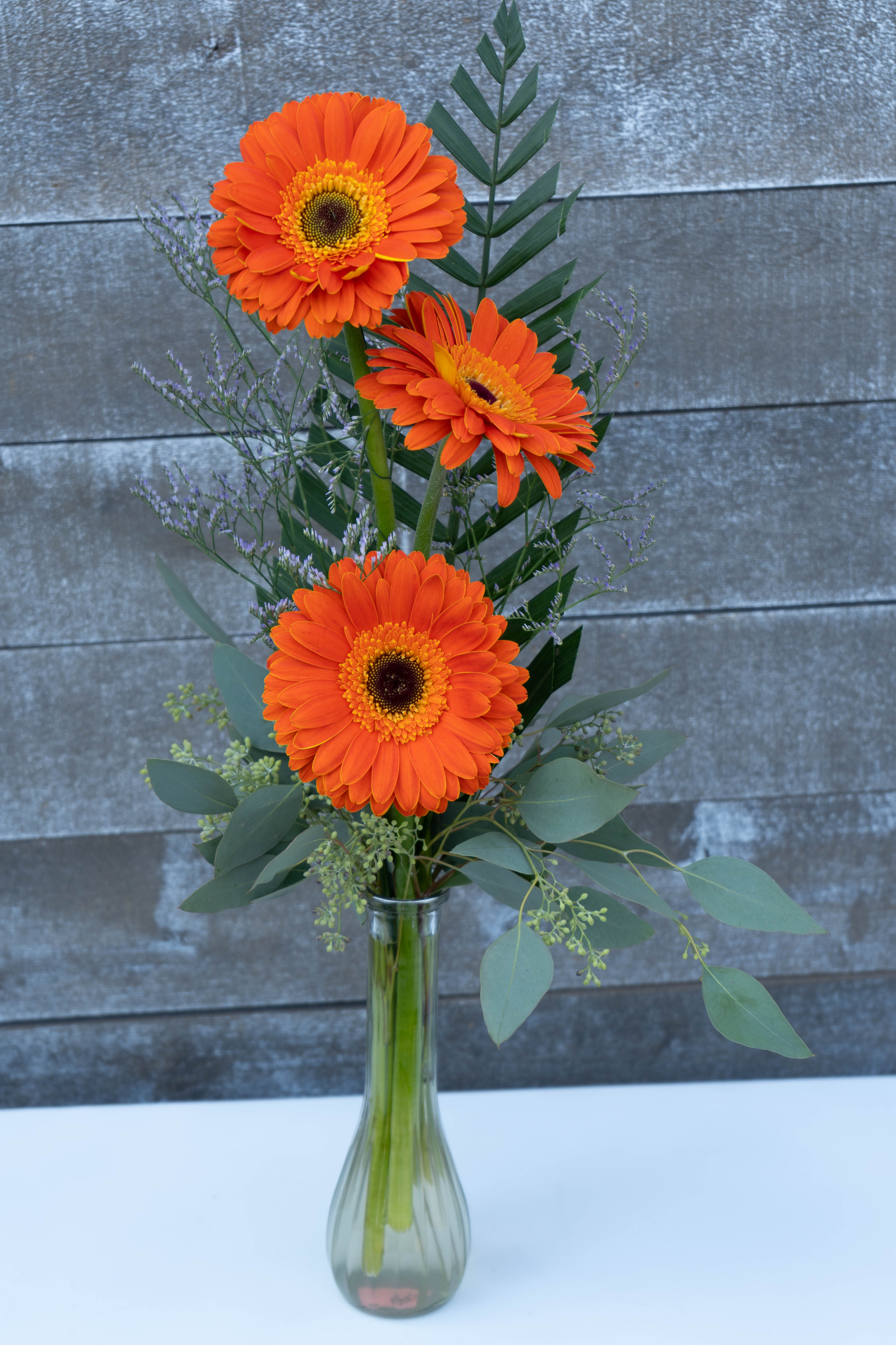3 orange gerbera daisy bud vase - Classic gorgeous orange Dutch gerbera daisies complimented with Greenery and light filler. Perfect gift for anyone!